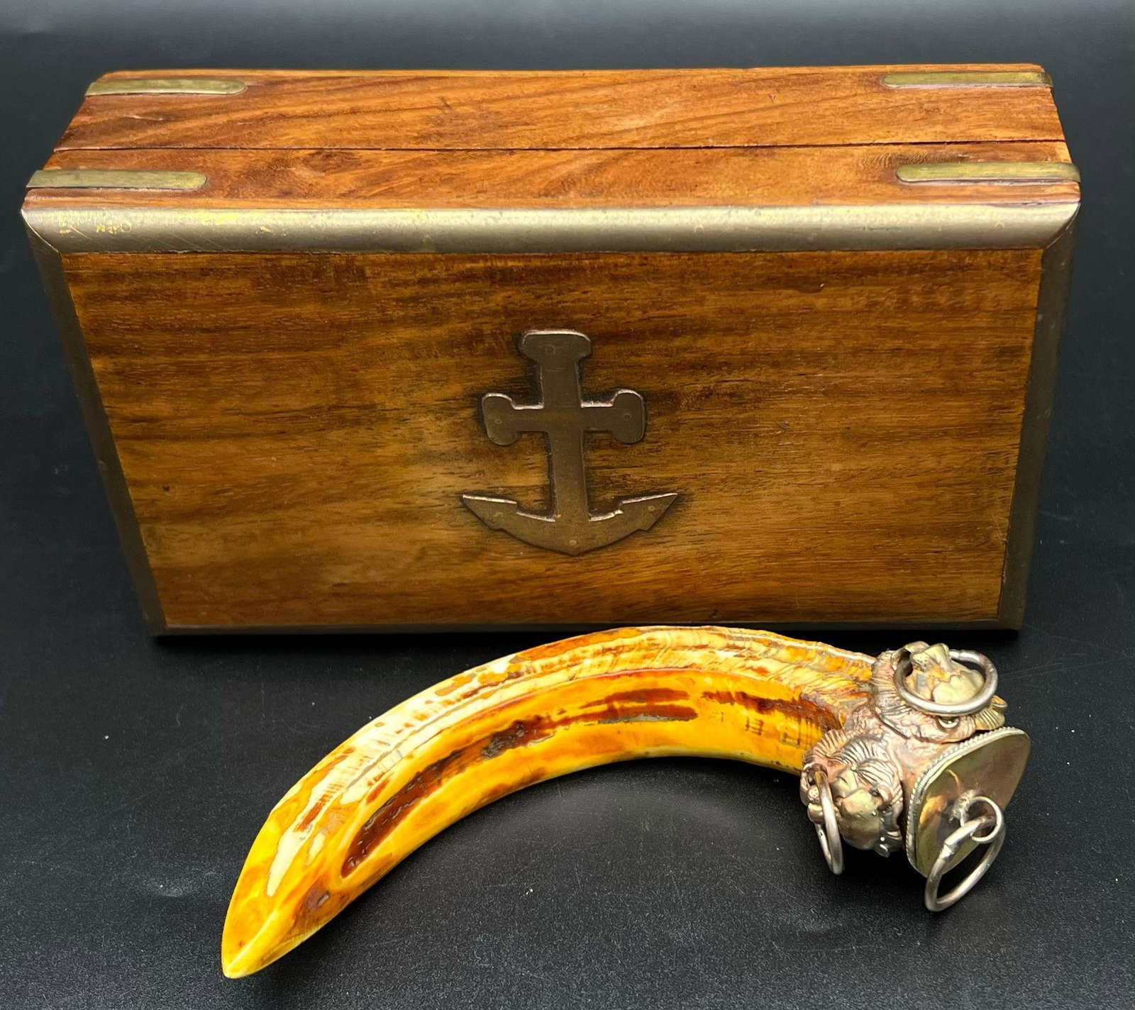 An antique TALISMAN with a wild boar’s task and a hand-crafted metal bale with four lion heads. The: An antique TALISMAN with a wild boar’s task and a hand-crafted metal bale with four lion heads. The item ispresented in rosewood casket with brass parts and an upside down anchor on top lid. Current