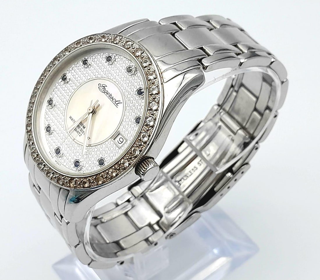 An Ingersoll Gems Quartz Watch. Stainless steel strap and case - 39mm. Mother of Pearl and Silver To: An Ingersoll Gems Quartz Watch. Stainless steel strap and case - 39mm. Mother of Pearl and Silver Tone Dial with blue stones on numbers. In working order.