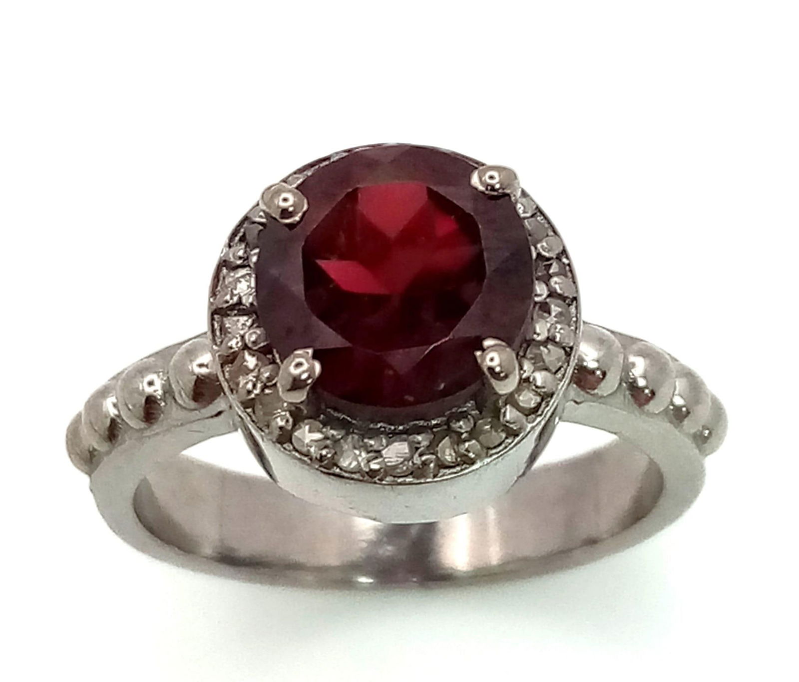 A Silver Garnet Ring with Rose cut diamond Surround. Garnet- 1.5ct. Diamond- 0.22ct. Size O. Comes: A Silver Garnet Ring with Rose cut diamond Surround. Garnet- 1.5ct. Diamond- 0.22ct. Size O. Comes with a presentation case.