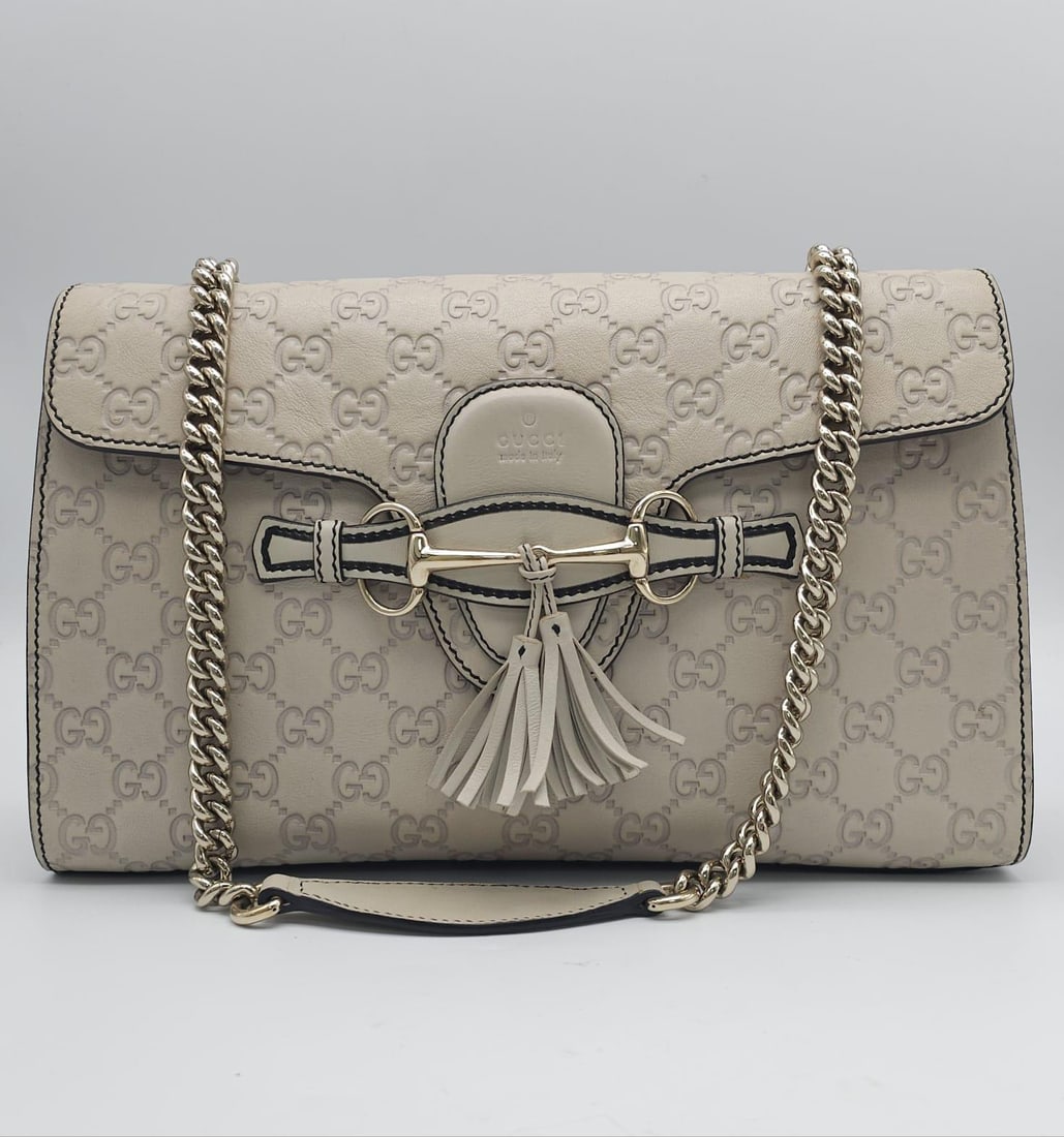 A Gucci Beige 'Emily' Bag. Monogram leather exterior with buckle and tassels. A chunky and heavy set: A Gucci Beige 'Emily' Bag. Monogram leather exterior with buckle and tassels. A chunky and heavy set silver toned chain strap. Beige canvas interior with three inner side pockets. 29.5cm length x 18cm