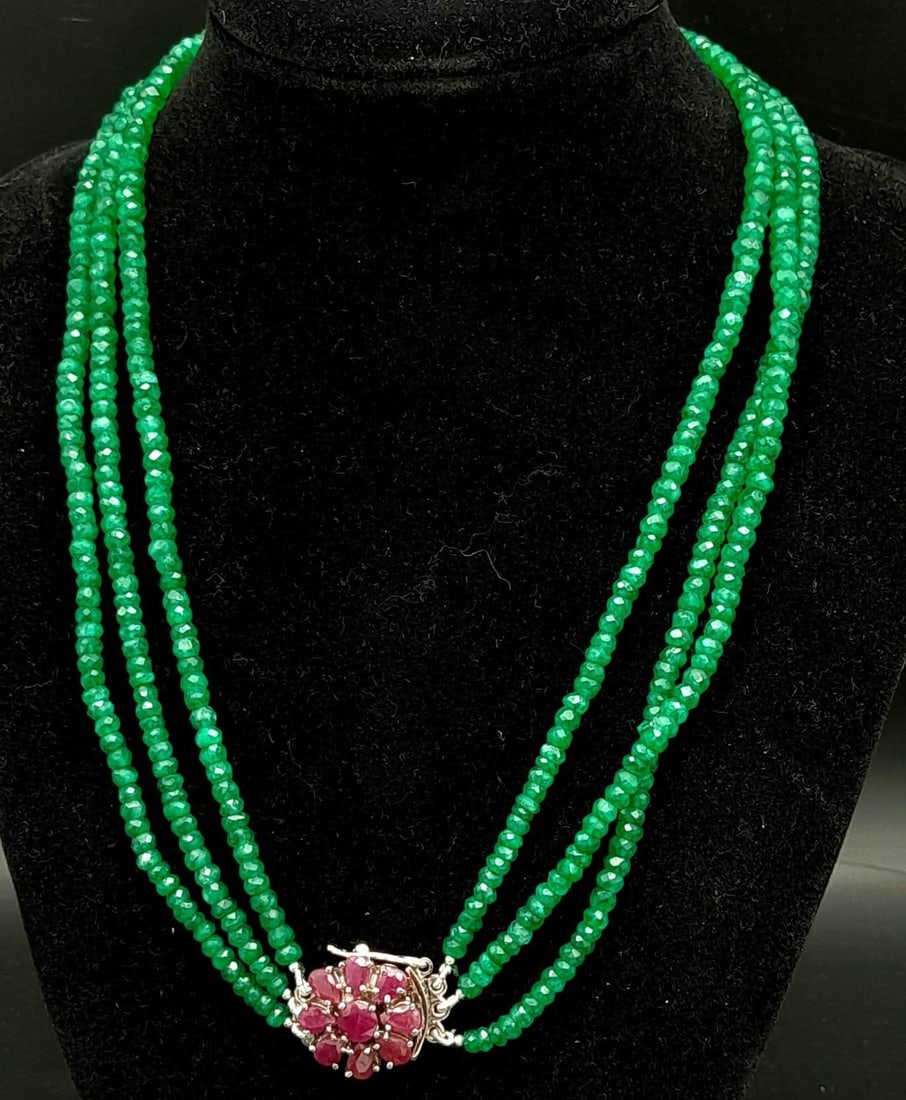 A Three Row Emerald Necklace with a Ruby and 925 Silver Clasp. 47.5cm in length, 250ctw emeralds,: A Three Row Emerald Necklace with a Ruby and 925 Silver Clasp. 47.5cm in length, 250ctw emeralds, 51g total weight.