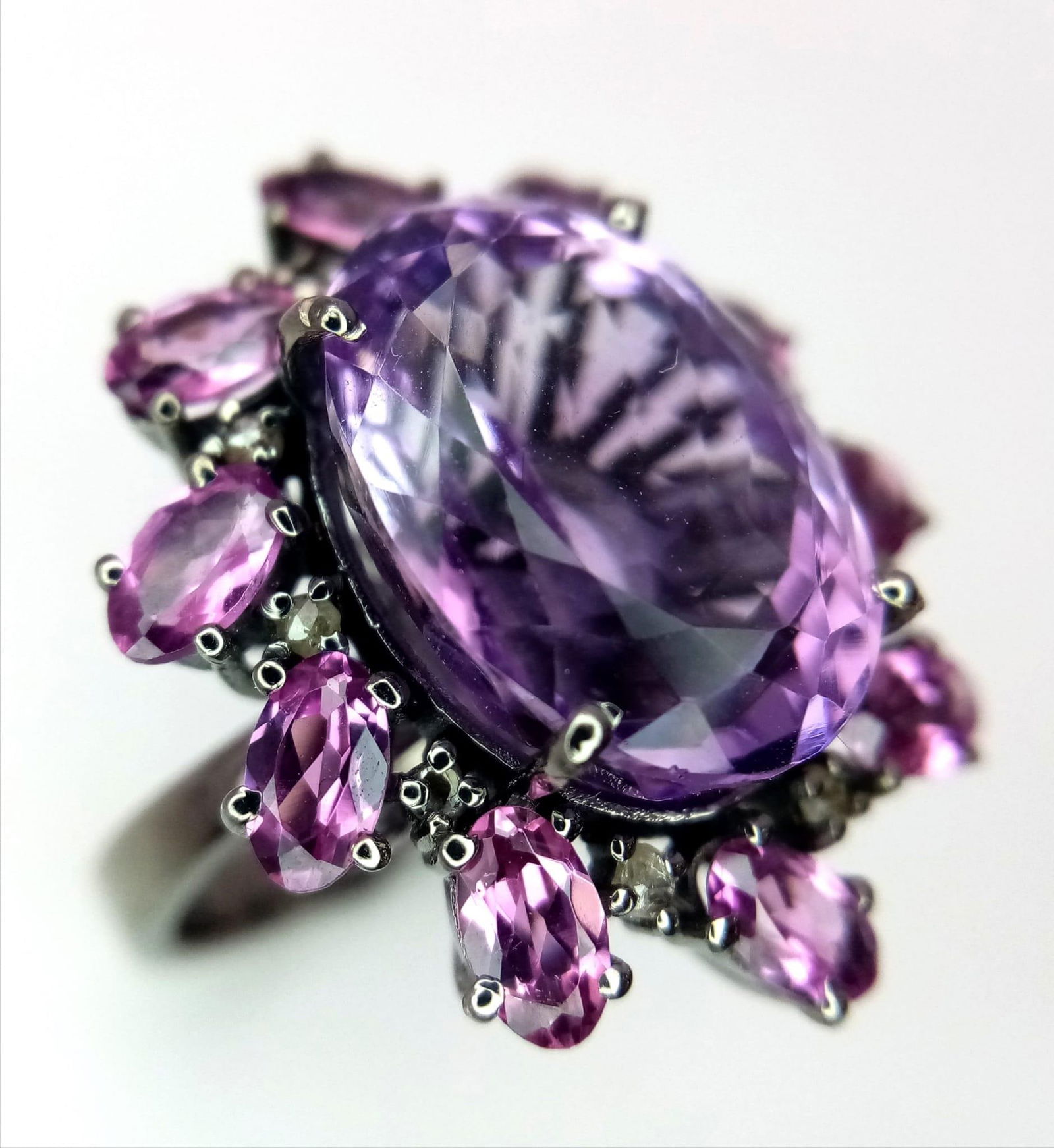 An Amethyst and Rhodolite 925 Silver Ring with Rose cut Diamond Accents. Amethyst - 13.55ctw.: An Amethyst and Rhodolite 925 Silver Ring with Rose cut Diamond Accents. Amethyst - 13.55ctw. Diamonds - 0.35ctw. Size N. 8g total weight. Comes with a presentation case.