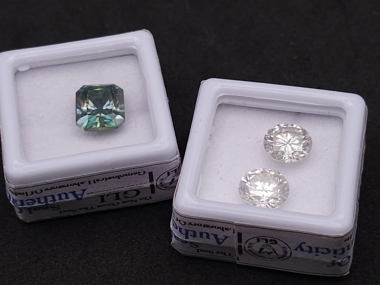 Two Moissanite Lots. A 4.480ct Radiant Cut Blue Moissanite, and a 4.450ctw pair of loose white: Two Moissanite Lots. A 4.480ct Radiant Cut Blue Moissanite, and a 4.450ctw pair of loose white moissanites. Both in sealed containers with certificates.