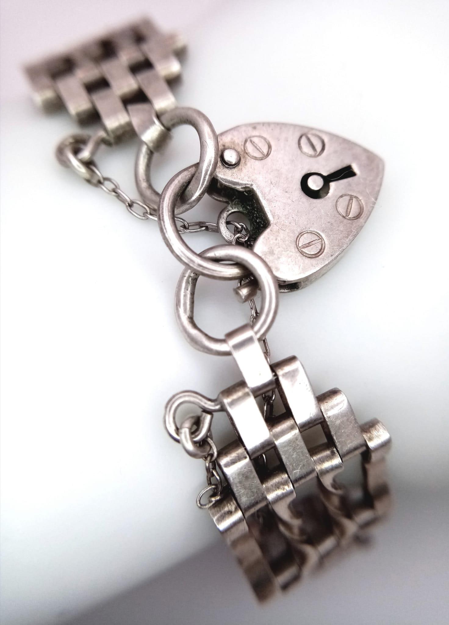 A vintage sterling silver gate bracelet with heart padlock silver charm. Total weight 15.8G. Total: A vintage sterling silver gate bracelet with heart padlock silver charm. Total weight 15.8G. Total length 19cm.