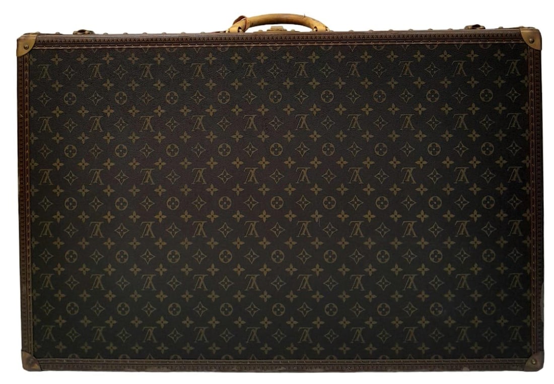 A Louis Vuitton Alzer 80 Monogram Large Sturdy Suitcase/Trunk. Monogram canvas and brown leather: A Louis Vuitton Alzer 80 Monogram Large Sturdy Suitcase/Trunk. Monogram canvas and brown leather exterior. Brass fittings and locks. Spacious cream interior. Dimensions: 80cm x 52cm x 26cm. Comes with