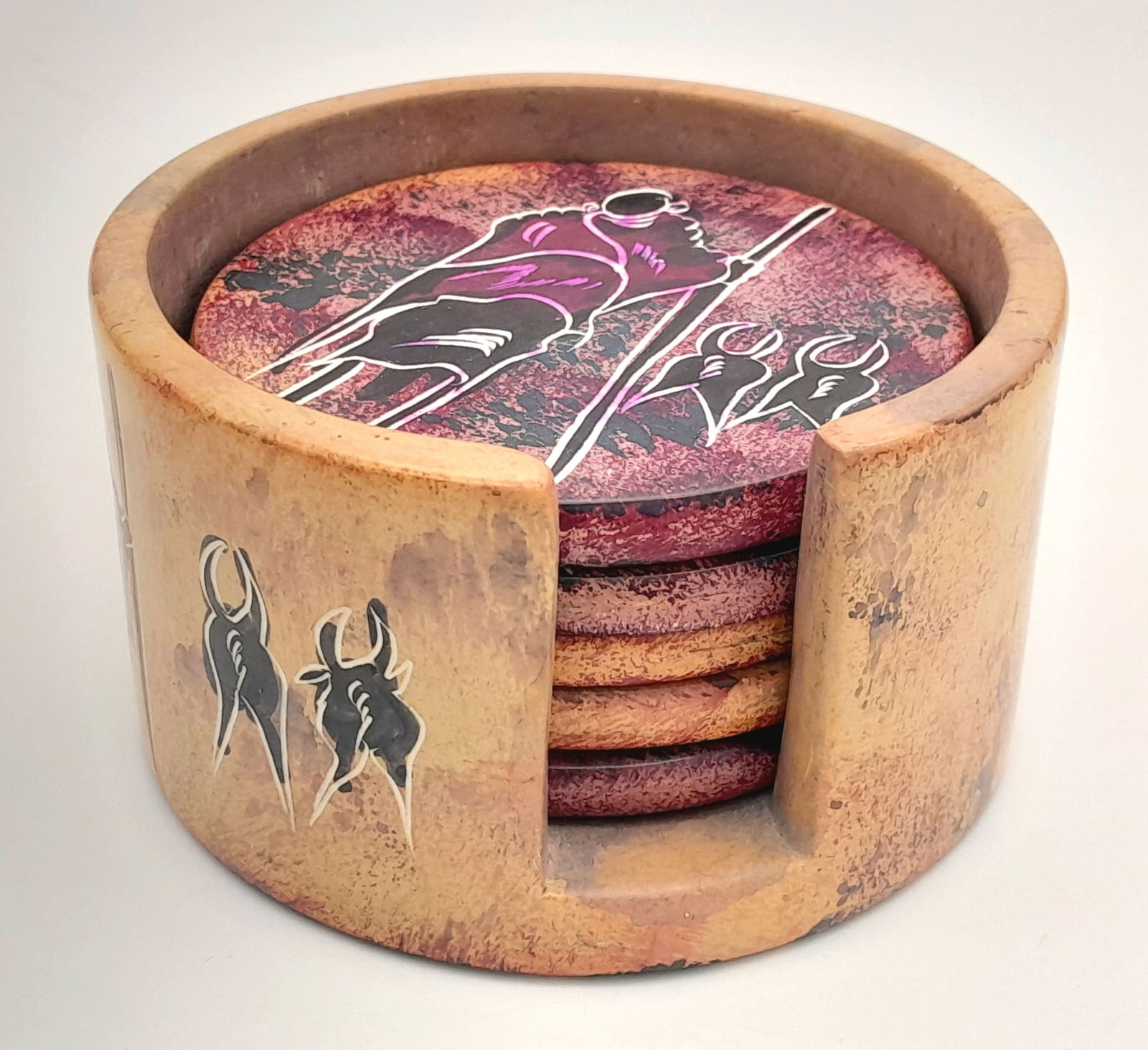 A set of 5 hand-painted round stone coasters with African tribal painting decoration. With: A set of 5 hand-painted round stone coasters with African tribal painting decoration. With matching holder. Diameter 8.5cm.