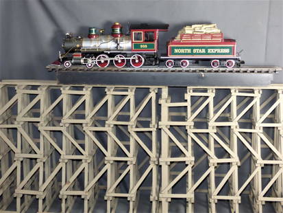 North Star Express #205 Train by Bachmann G Scale: North Star Express #205 G Scale 4-6-0 Locomotive with Tender by Bachmann. Engine stands on custom made wooden ramp/ bridge stand. Stand is two sectional and measures approx.59" x 23". Condition: Used,