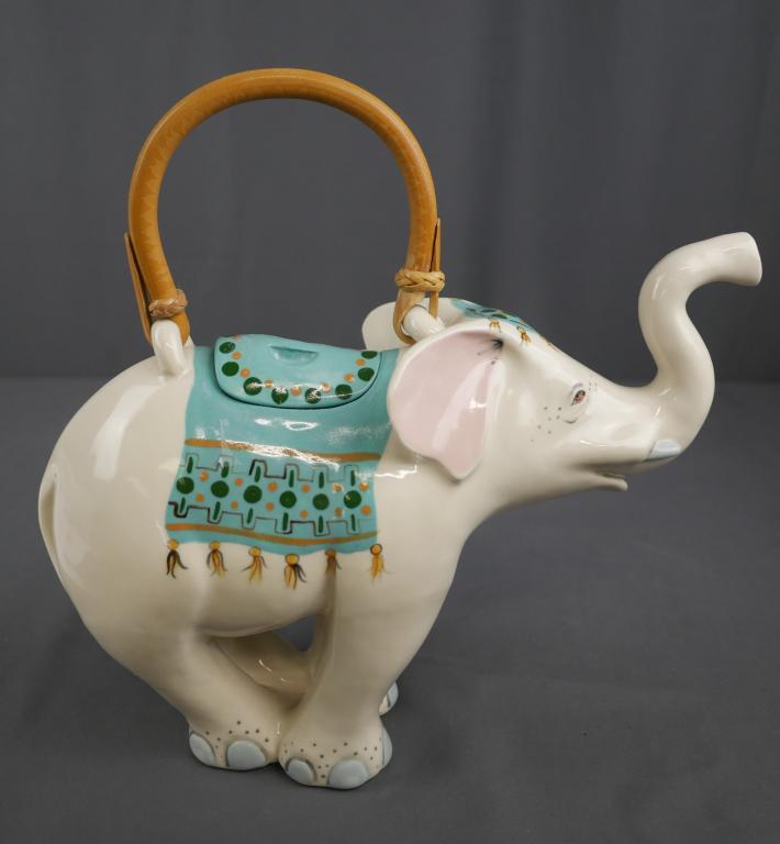 Vintage "Animals & Co." Decorative Elephant Teapot: Lovely ceramic elephant teapot circa 1985 by "Animals & Co." pottery company. Vibrant hand-painted details in teal and gold accent the sweet elephant's face with a wicker handle. Hand signed on bottom
