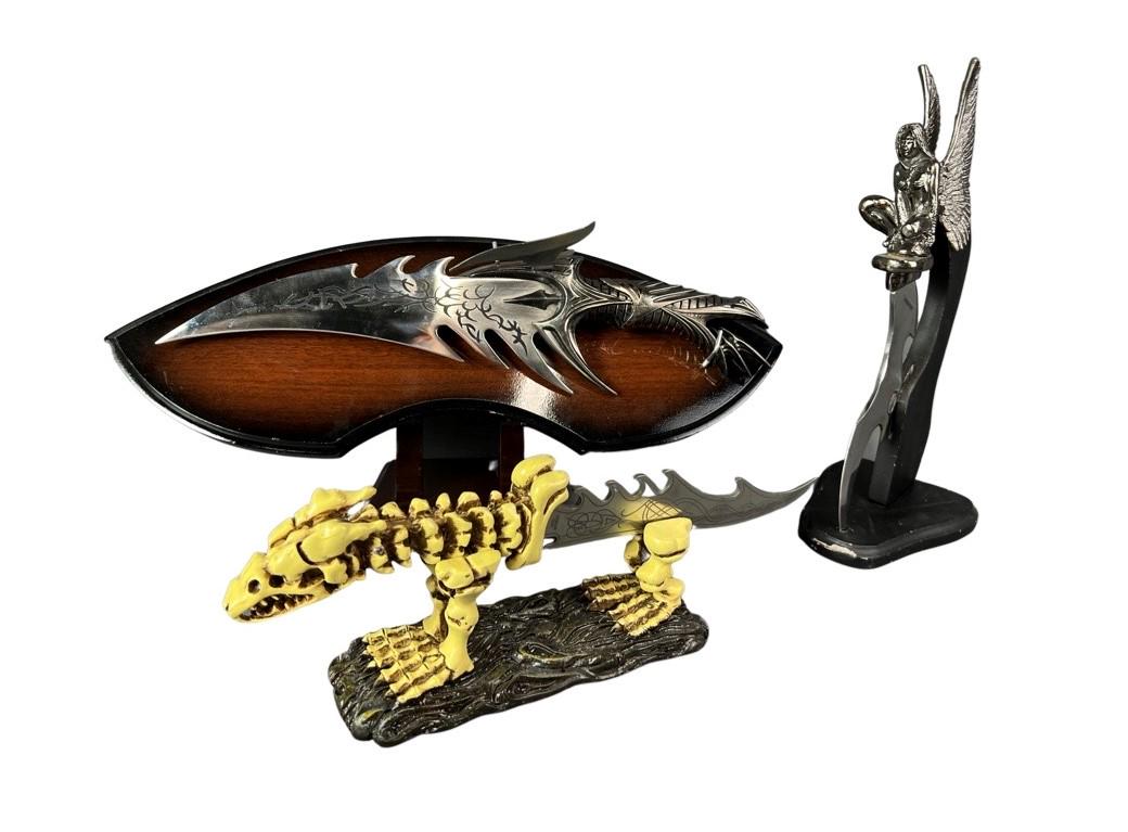Lot of Figural Fantasy Daggers/ Knives w/ Display: 3 Figural Fantasy Daggers/ Knives with Display Stands. Measure 15 1/2"-12 1/2" long. Good Condition.