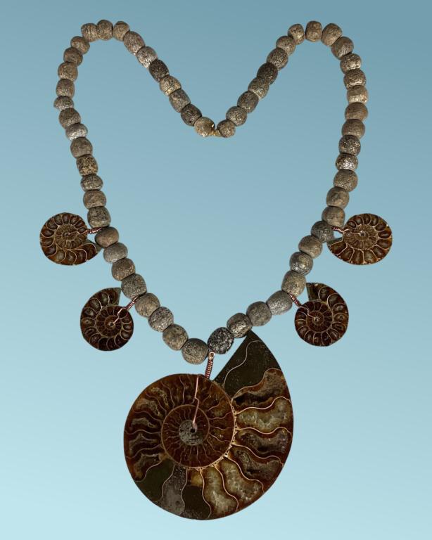 Fossil Ammonites & Carved Mastodon Bones Necklace: Necklace made of Fossilized Carved Mastodon Bone Beads, one large Fossil Ammonite Pendant and foursmaller Fossil Amonite Pendants (35-80 mil. yrs old. Necklace is approx. 26" long. Largest Fossil Amon