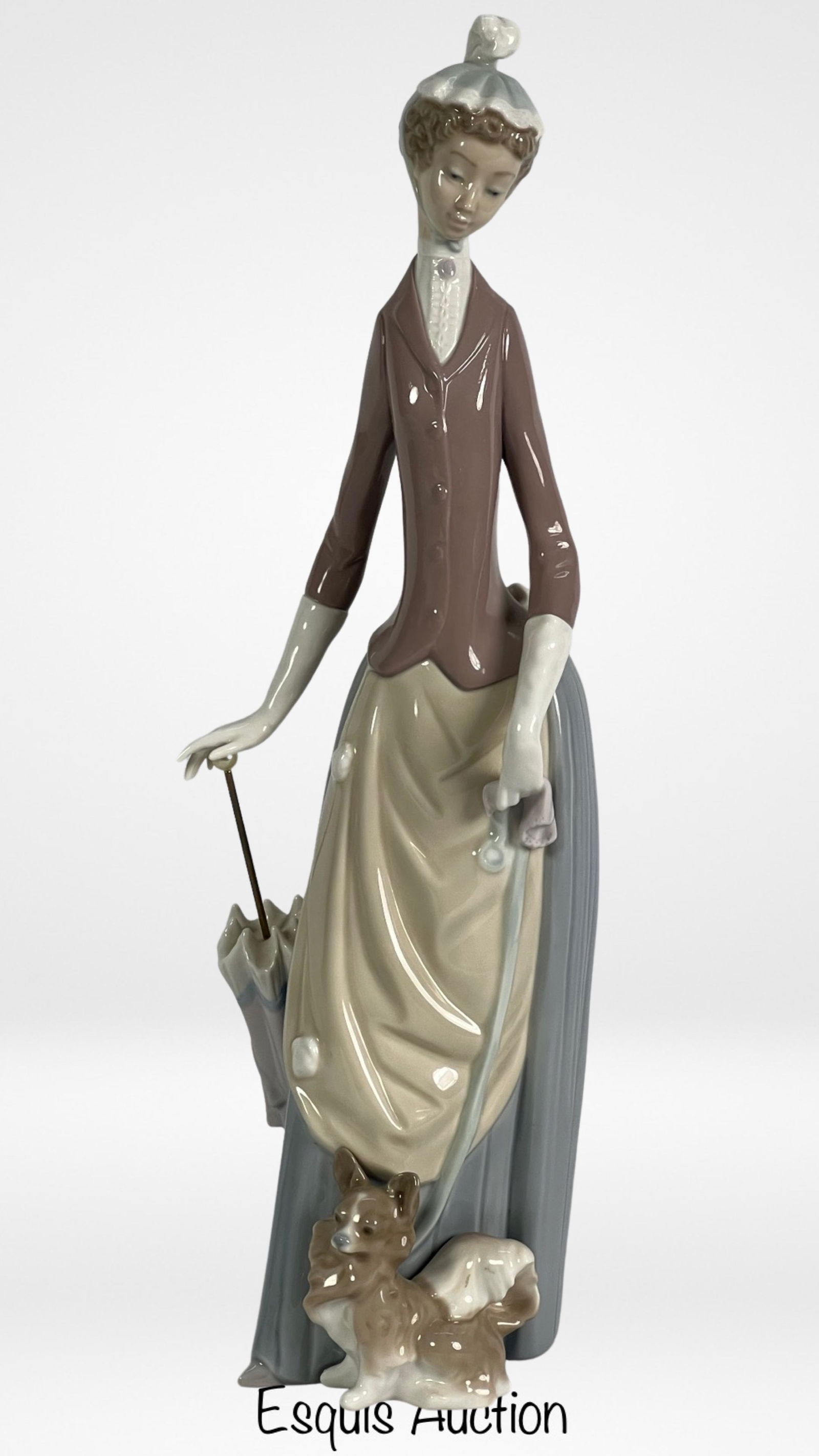 Lladro Lady with Dog & Umbrella Porcelain Figurine: The Lladro "Lady with Dog & Umbrella" 4761 Porcelain Figurine is a captivating masterpiece that exudes elegance and grace. Standing at 14" tall, this figurine portrays a lady holding an umbrella with