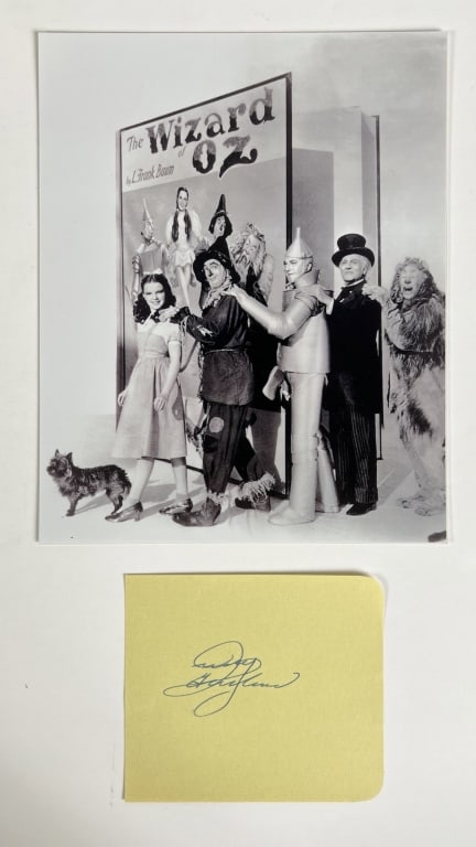 Judy Garland Autograph w/ Wizard of Oz Photo: Capture the magic of "The Wizard of Oz" with this Judy Garland Autograph paired with an 8" x 10" Cast photograph. The legendary Judy Garland, known for her unforgettable portrayal of Dorothy in the ti