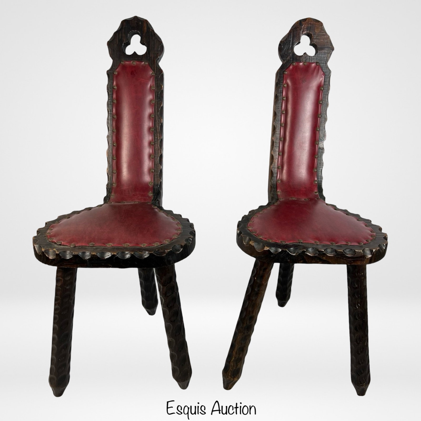 Vintage Carved Wood Birthing Chair Style Stools: Pair of vintage carved wood stools designed in the style of birthing chairs. These stools feature a unique gothic-inspired backrest with a keyhole cutout, red leather upholstery with brass nailhead tr