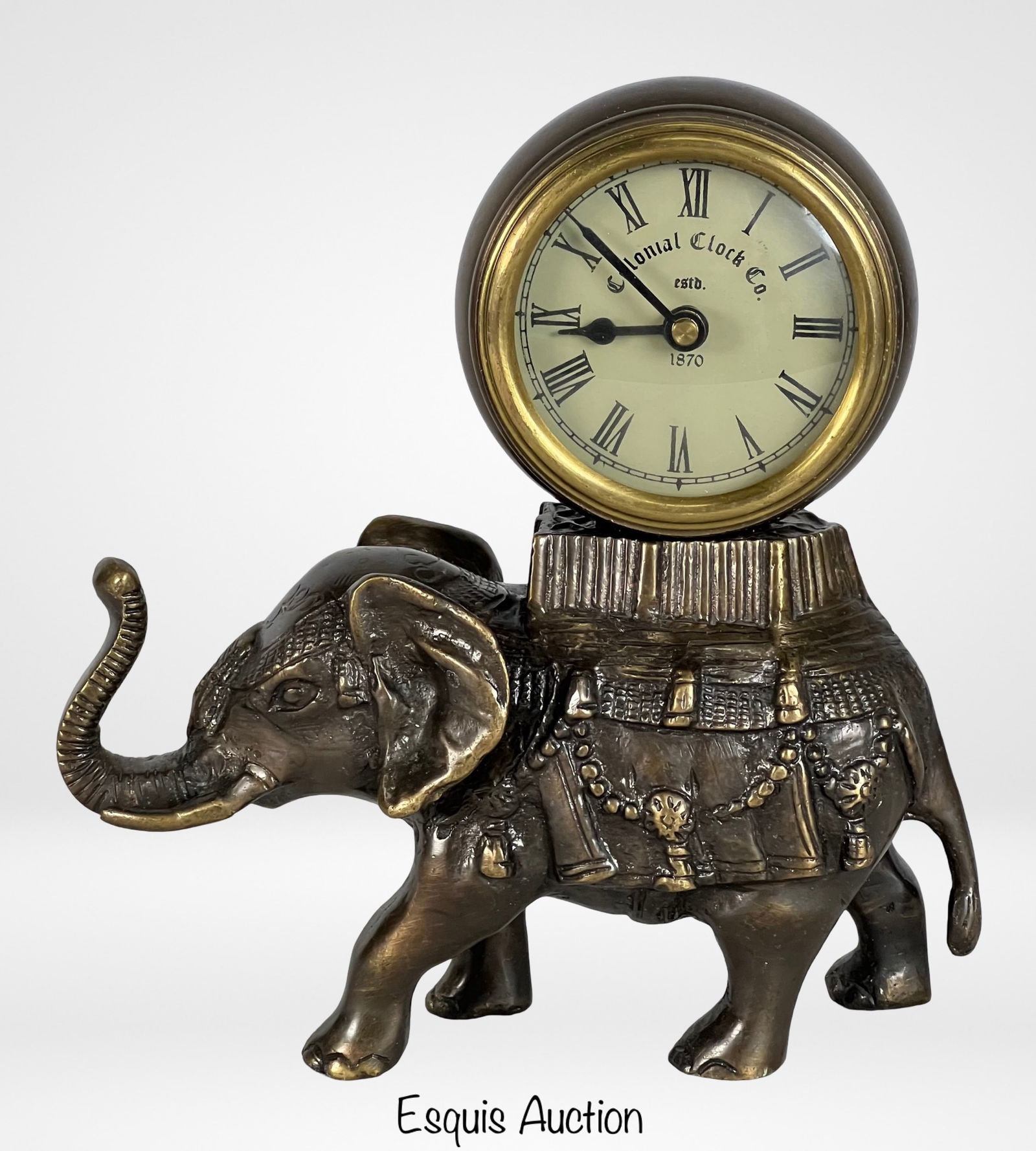 Colonial Clock Co Elephant Mantel Clock: This charming mantel clock, crafted by the Colonial Clock Co., features a detailed elephant figurine as its base. The clock face is set atop the back of the elephant, which is adorned with intricate o