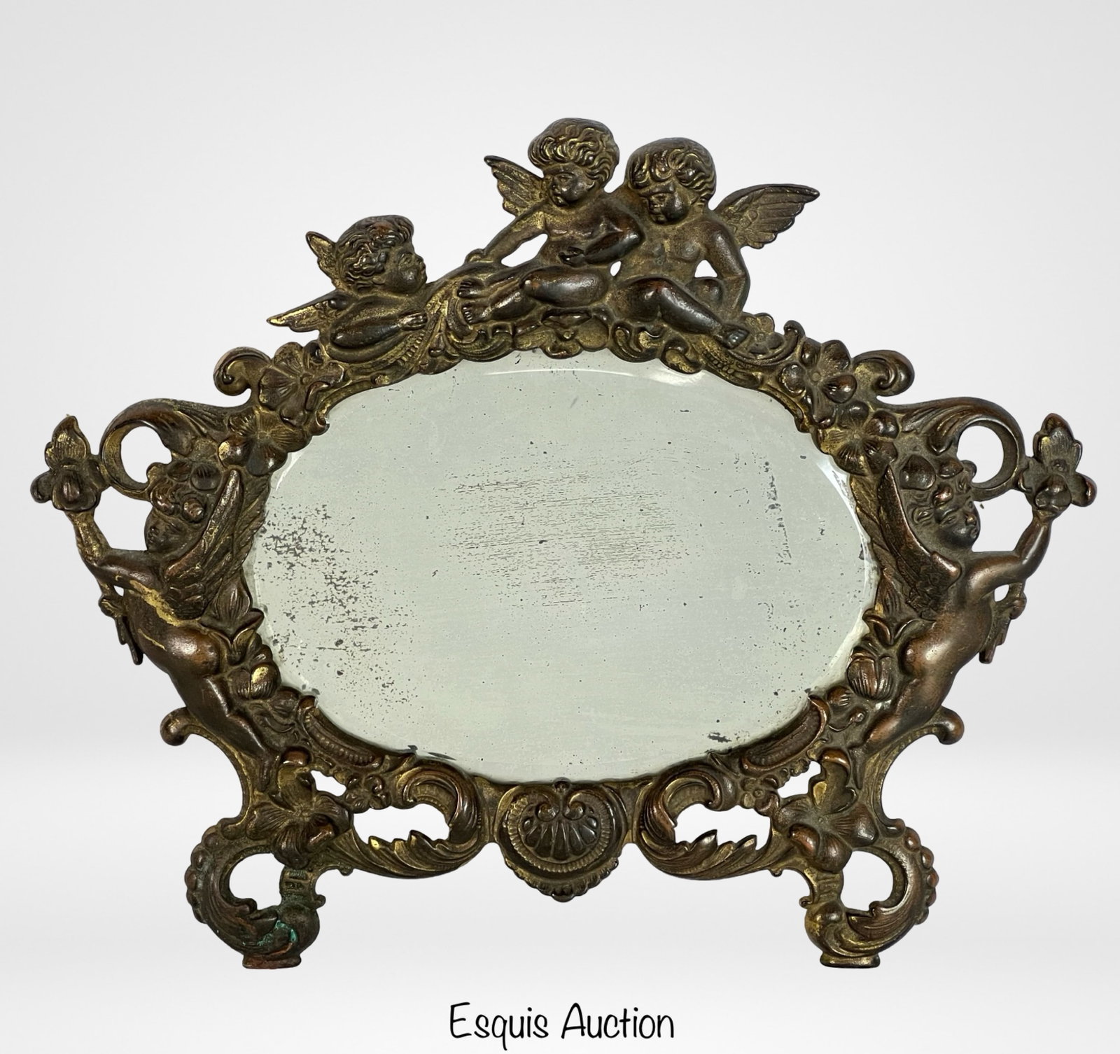 Art Nouveau Bronze Boudoir Mirror with Cherub: This is an exquisite early 20th-century Art Nouveau bronze mirror, measuring 11 1/2" x 10 1/2". The mirror is ornately designed with a playful and romantic cherub motif. The cherubs, with delicate win