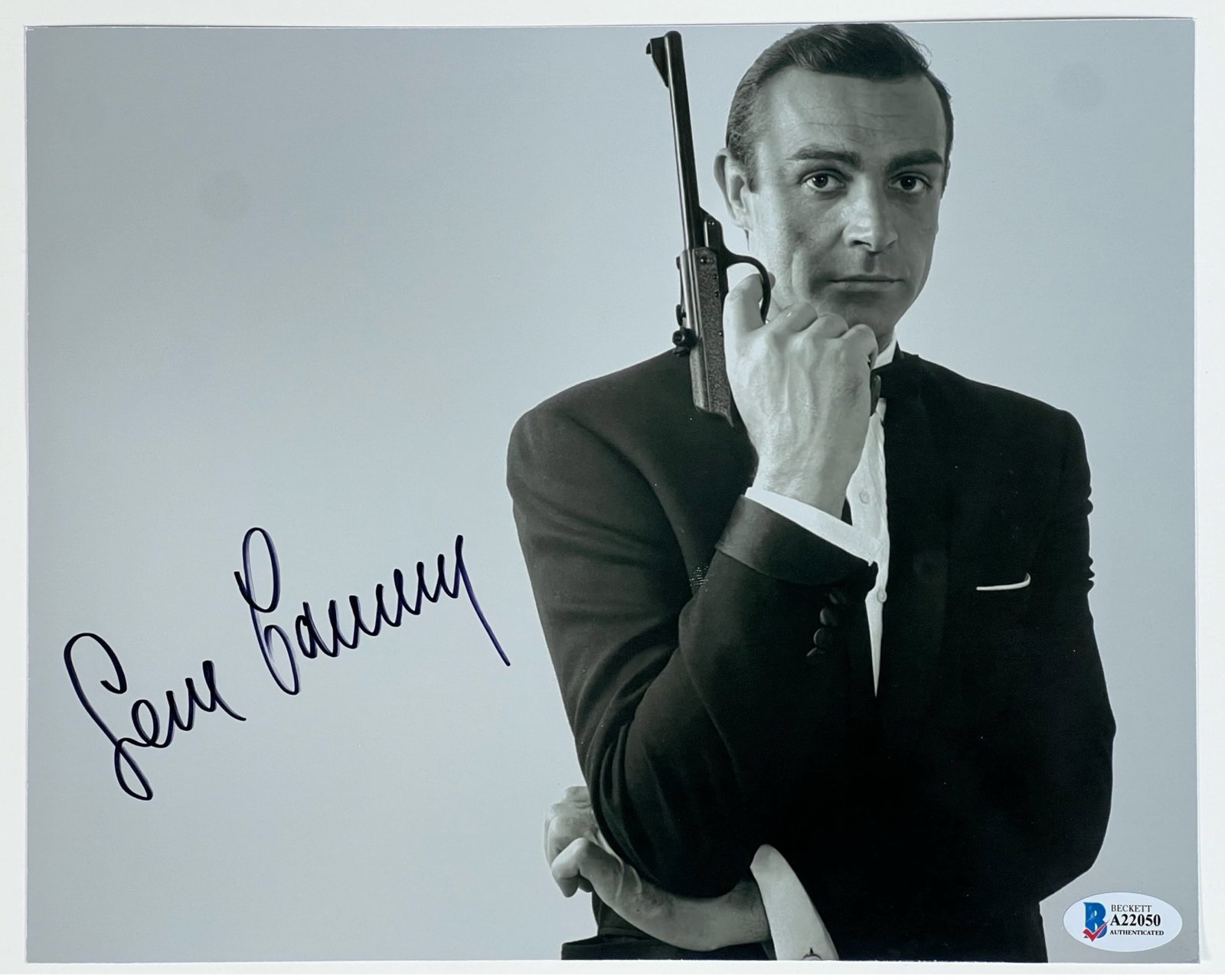 Sean Connery James Bond Autographed/ Signed Photo: This iconic black and white photograph features Sean Connery in his most famous role as James Bond, holding a pistol in the classic 007 pose. The photograph is boldly signed by Connery in black ink. A