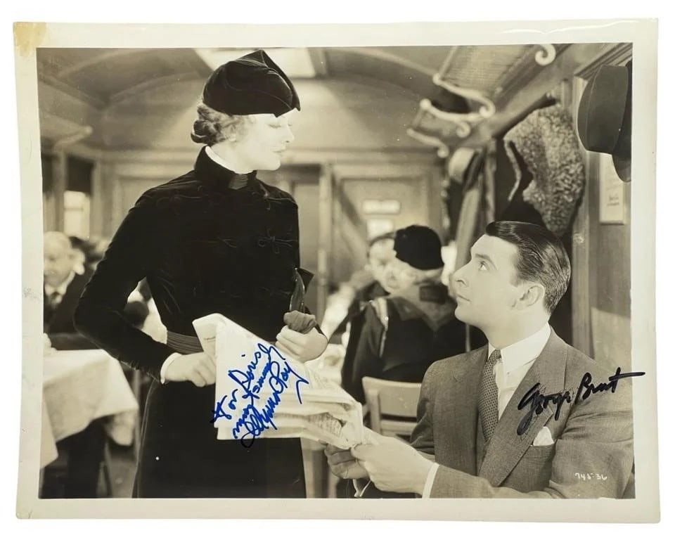 George Brent & Myrna Loy Autographed Photo: This lot features an 8" x 10" black and white photograph autographed by Hollywood stars George Brent and Myrna Loy. Both signatures are prominently displayed, with George Brent's autograph in black in