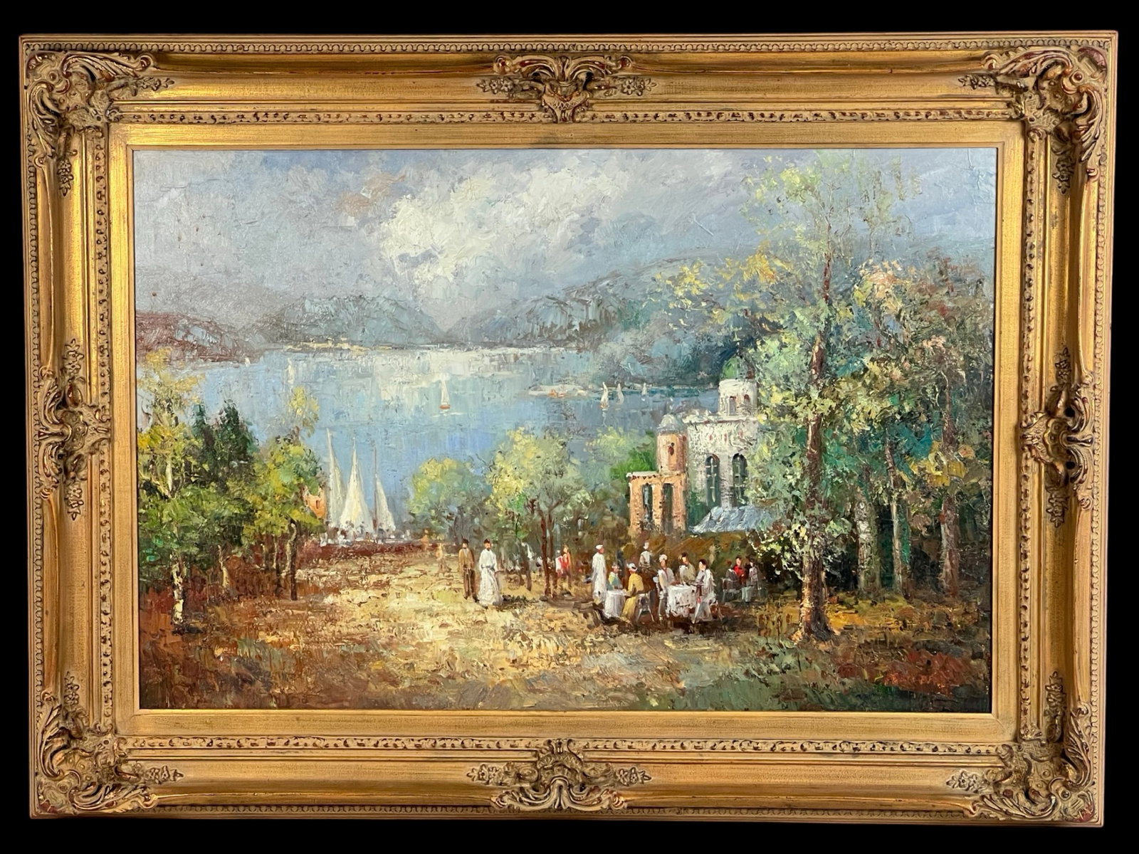Kunsthart Nimil - Impressionist Landscape Painting: This vibrant oil painting by Kunsthart Nimil depicts a serene lakeside scene with figures gathered near a villa. The painting features a backdrop of a glistening lake with sailboats, framed by lush tr