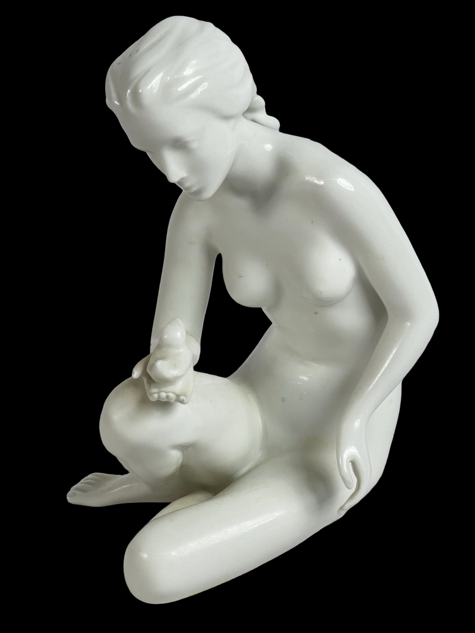 Royal Dux- Nude Girl with Bird Porcelain Figurine: This elegant Royal Dux porcelain figurine depicts a serene nude girl seated, gently holding a small bird on her knee. Standing at 7 1/2" tall, this piece showcases the refined craftsmanship and smooth
