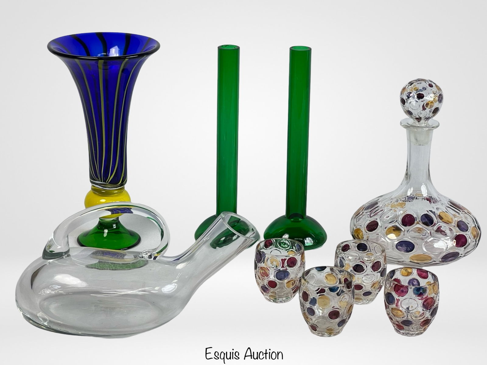 Collection of Colorful Handcrafted Art Glass: A vibrant collection of handcrafted glass pieces, featuring a striking blue and yellow vase, two green candlesticks, and a unique multicolor polka-dot Bohemian glass decanter set. The decanter is comp
