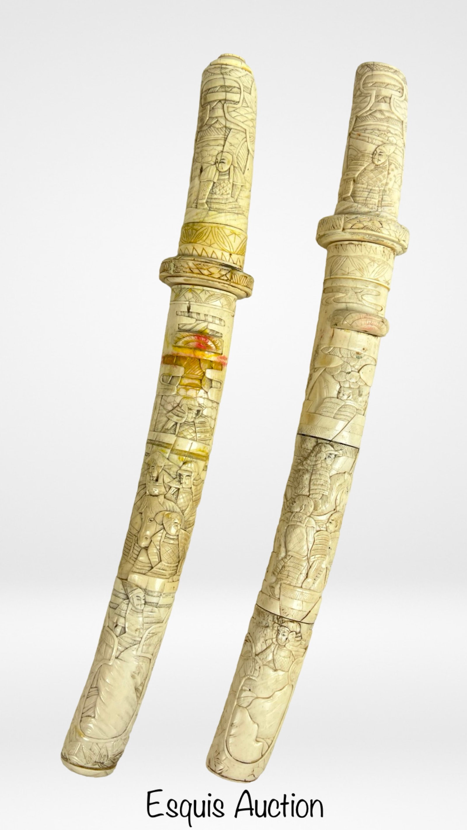 Pair of Asian Style Carved Bone Daggers w/ Sheaths: These intricate bone daggers feature ornate hand-carved designs on both the blades and their sheaths, depicting figures and scenes in a detailed relief. The craftsmanship showcases traditional Asian m
