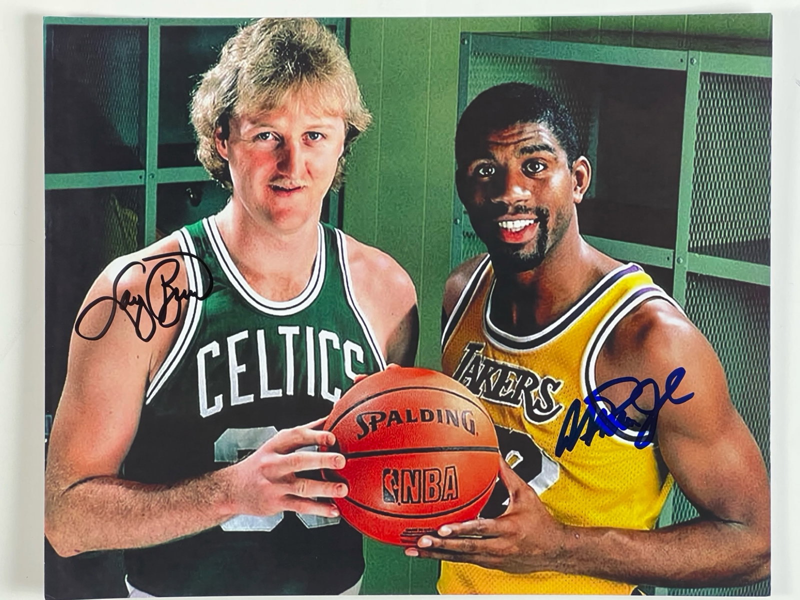 Larry Bird & Magic Johnson Dual-Signed Photograph: Color photograph featuring NBA legends Larry Bird and Magic Johnson posing together in their iconic team jerseys, with Bird representing the Boston Celtics and Johnson in the Los Angeles Lakers unifor
