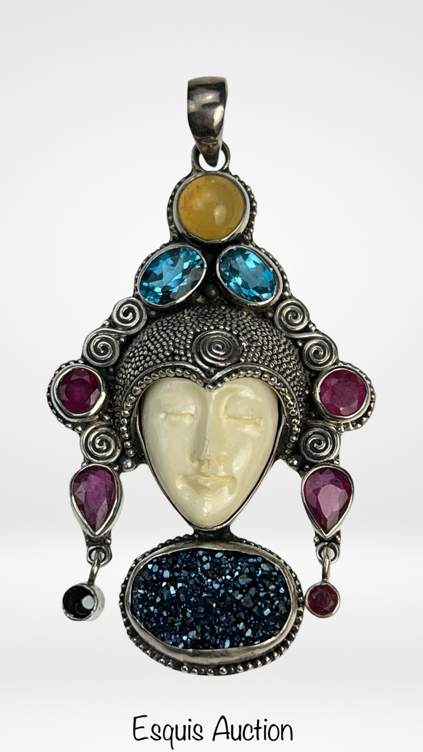 Sajen Sterling Carved Face Multi-Stone Pendant: Exquisite vintage Sajen sterling silver pendant featuring a delicately carved bone face framed by intricate silverwork. The headdress is adorned with faceted blue topaz, ruby, and citrine stones, acce