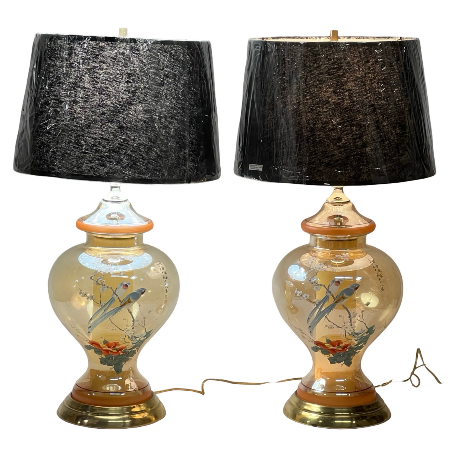 air of Chinese Glass Lamps w/ Birds & Floral Motif: Elegant pair of Chinese glass lamps featuring hand-painted birds perched on flowering branches, complemented by delicate calligraphy. The amber-hued glass bodies are accented with red and gold trim, r