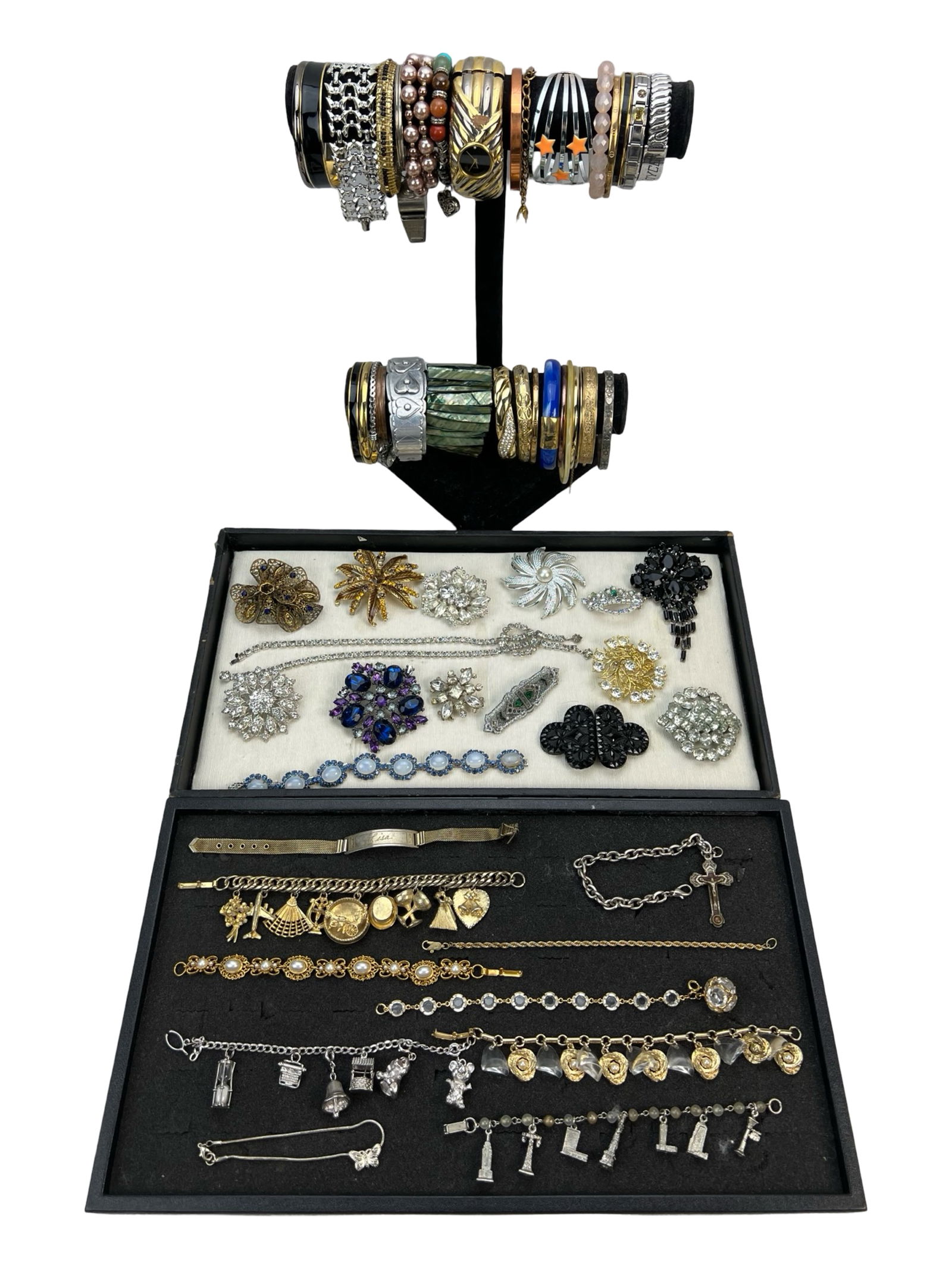 Vintage Costume Jewelry Collection: A diverse collection of vintage costume jewelry, including an assortment of bangles, charm bracelets, brooches, and rhinestone-adorned pieces. The lot features a variety of designs, from intricate fil