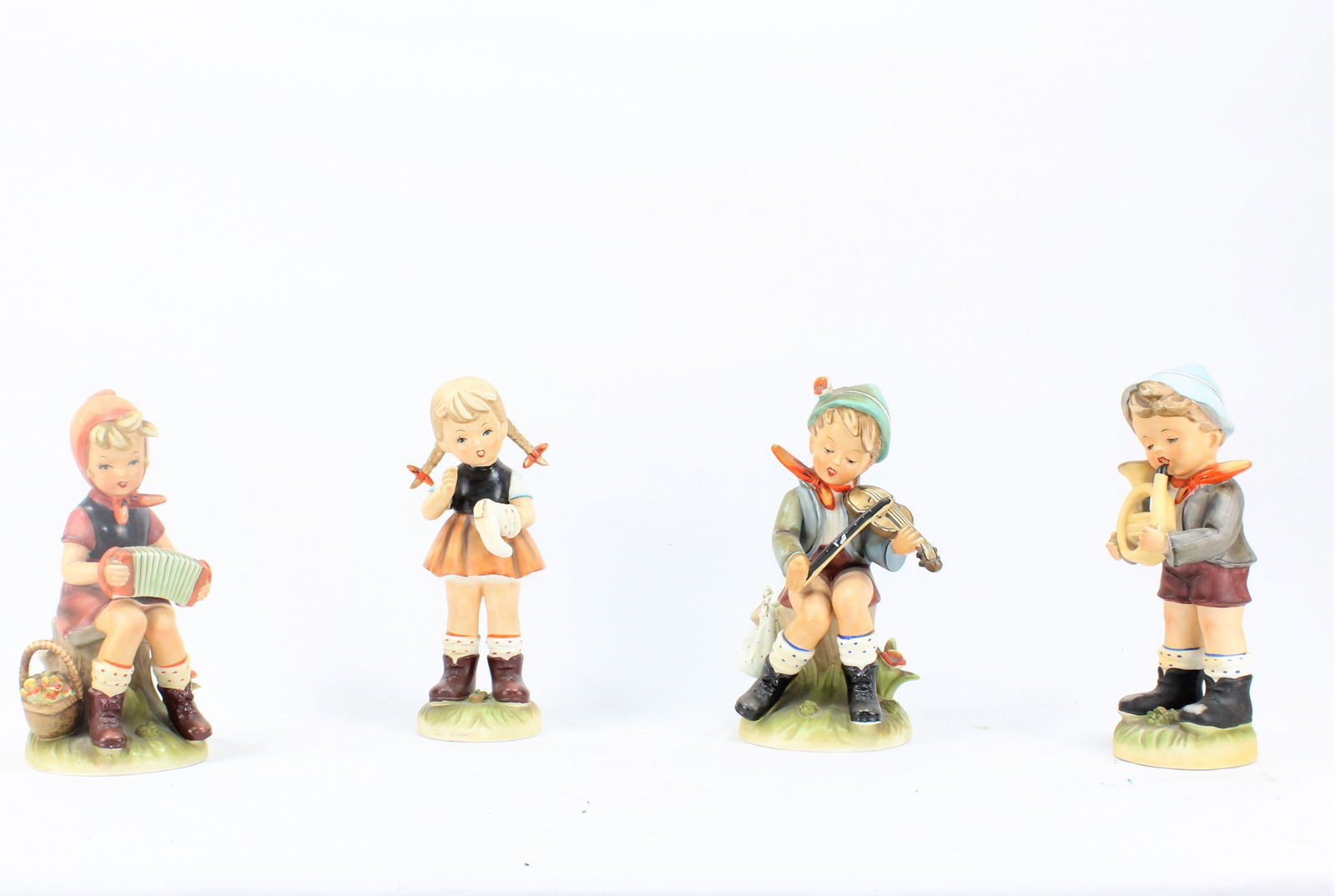 Goebel Hummel Style Porcelain Figurine Set of Four, Musical Children Theme: Charming set of four Goebel Hummel-style porcelain figurines depicting children engaged in musical activities. Each hand-painted figurine showcases intricate details and soft pastel tones, characteris