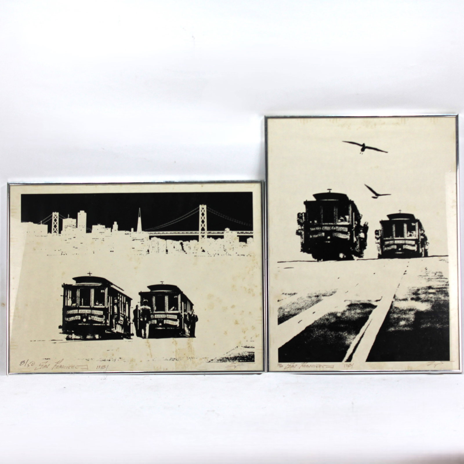 Jan Francizel Black & White Cable Car Prints: The artwork captures the essence of the city's vintage charm with bold contrasts and fine details. Both pieces are framed in simple silver-tone frames, showing some wear consistent with age. The print