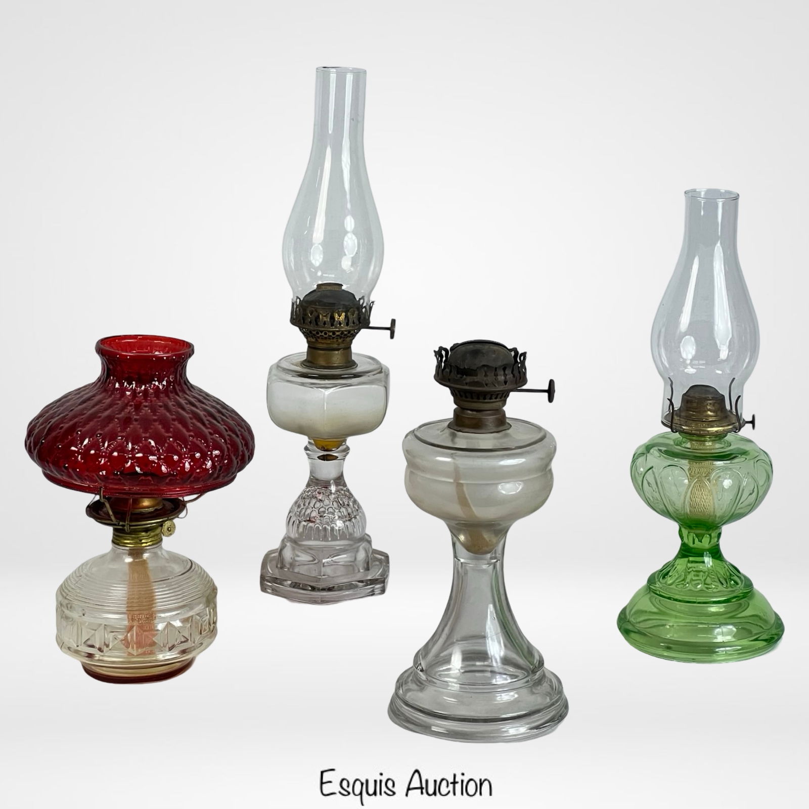 Antique & Vintage Kerosene Oil Lamps - Lot of 4: A collection of four antique and vintage kerosene oil lamps, each showcasing unique glass designs and metal burner mechanisms. The tallest lamp measures 20 1/2" x 5". This set includes clear, green, a