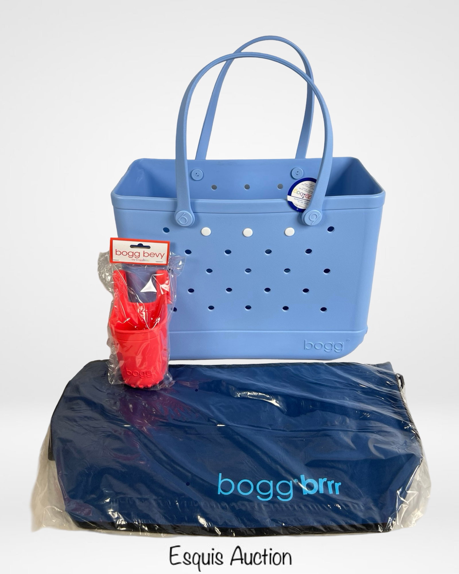 Bogg Bag with Cup Holder & Cover- New: Brand new Bogg Bag in light blue, complete with a matching Bogg Brrr cooler cover and a red Bogg Bevy cup holder attachment. Measures approximately 19" x 9" x 14". Perfect for those looking for a styl
