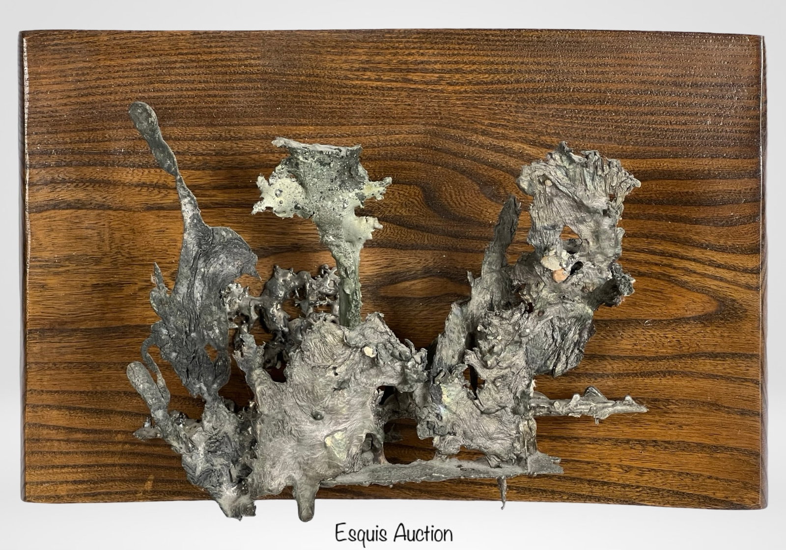 Brutalist Molten Metal Wall Sculpture: Brutalist-style wall sculpture composed of molten aluminum or pewter-cast metal abstract forms mounted on a richly grained ash wood plaque. The freeform metalwork is reminiscent of lava flow or coral 