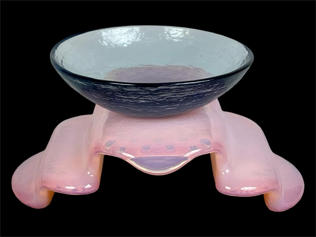 Contemporary Art Glass Bowl on Sculptural Base: Unique contemporary art glass centerpiece featuring a shallow, textured bowl in translucent aqua resting atop a sculptural pink opalescent base. The organic base design evokes a soft, biomorphic form 