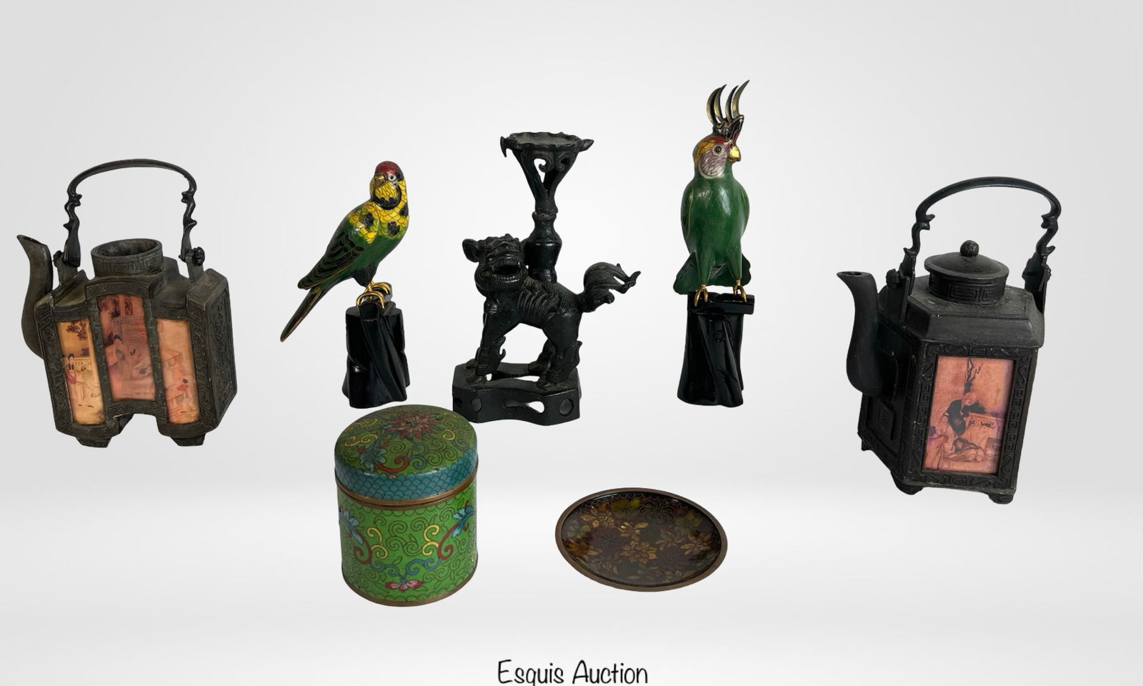 Asian Decorative Objects- Cloisonne, Enamel, Cas: Eclectic group featuring two painted metal teapots with figural panel insets, a cast metal foo dog candleholder, and two colorful cloisonnÃ© parrots on black bases. Also includes a green cloisonnÃ�