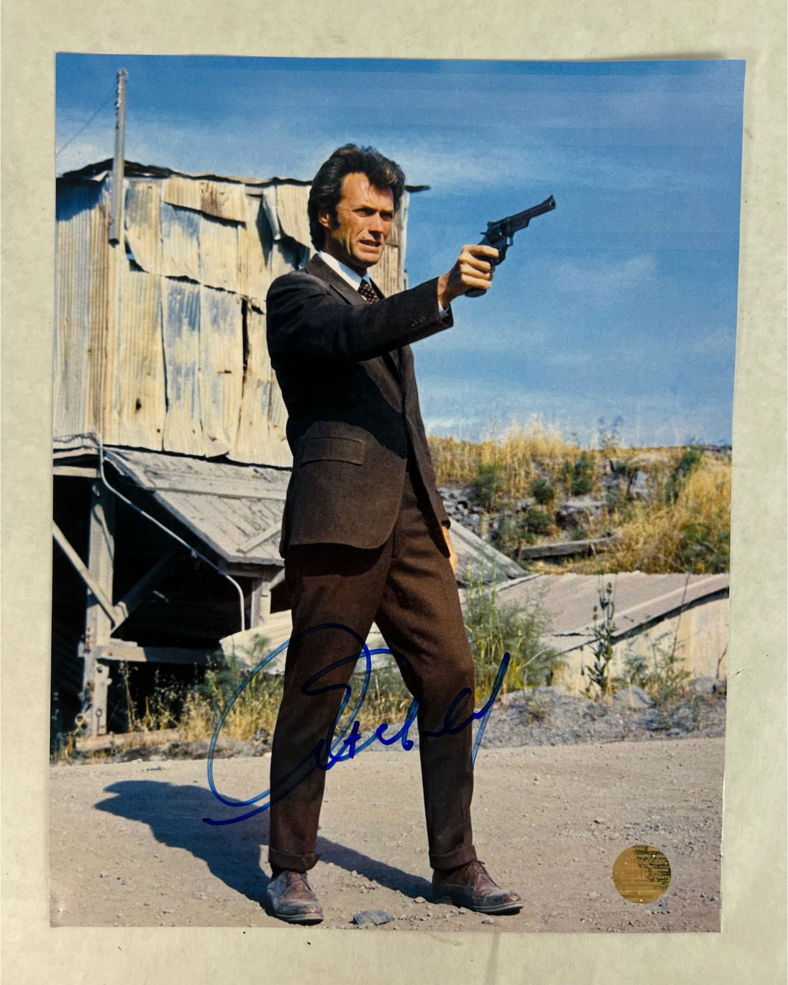 Clint Eastwood Autographed Dirty Harry Photograph: Iconic photograph of Clint Eastwood in his legendary role as Inspector "Dirty" Harry Callahan, captured mid-scene aiming his signature .44 Magnum revolver in a gritty outdoor setting. Signed boldly in