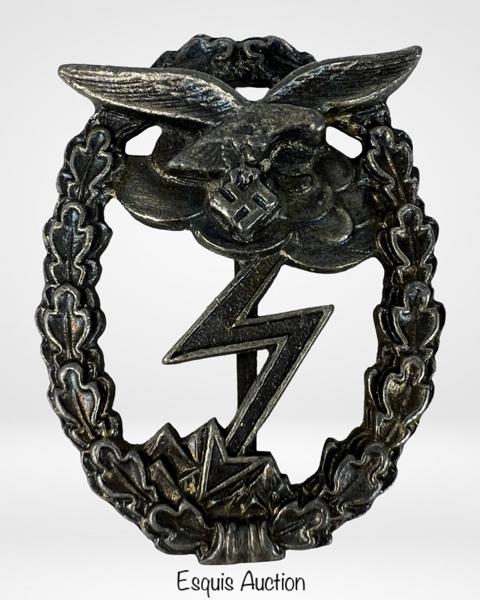 WWII German Luftwaffe Ground Assault Badge: World War II-era German Luftwaffe Ground Assault Badge, constructed in dark-toned metal with intricate detailing. The badge features an eagle clutching a bolt of lightning above a cloud, surrounded by