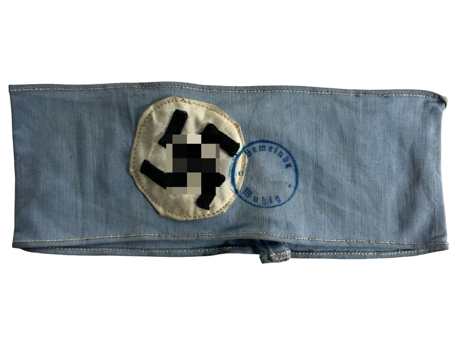 WWII-Era German Blue Cloth Armband: WWII-era German military cloth armband constructed of blue cotton with a hand-embroidered black insignia stitched to a white roundel at the center. The armband bears a circular ink stamp in blue, part