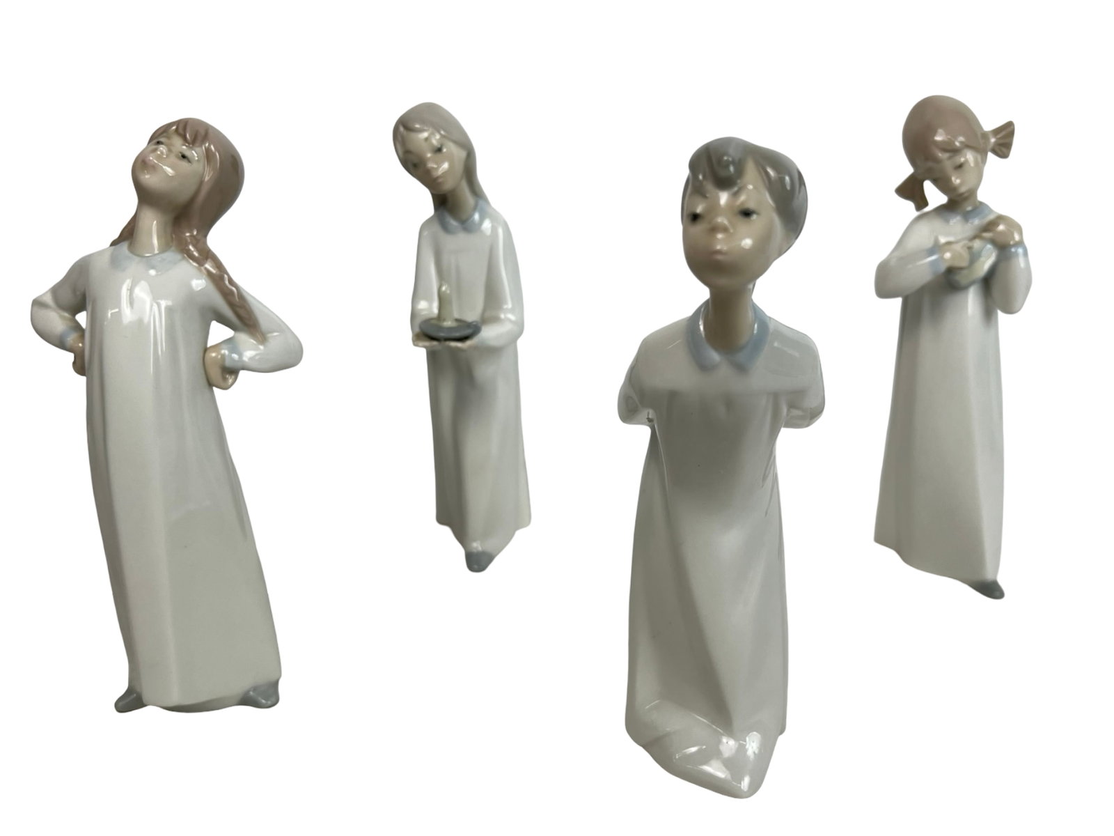 Lladro Porcelain Figurines - Set of Four: Charming collection of four Lladro porcelain figurines, each finely crafted and hand-painted in soft pastel tones with a high-gloss finish. The set depicts expressive children in different poses, show