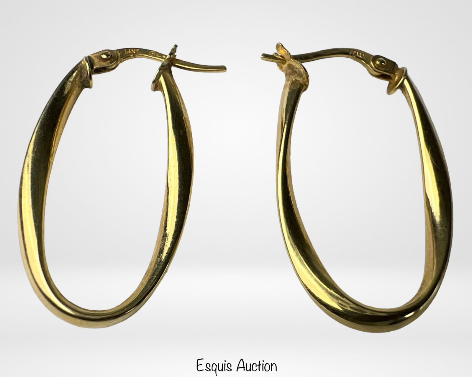 14K Yellow Gold Hoop Earrings: Classic pair of 14K yellow gold hoop earrings with a modern elongated oval design. Measuring 1 1/4" x 3/4", these hoops feature a polished finish and secure hinged latch backs for comfortable wear. El
