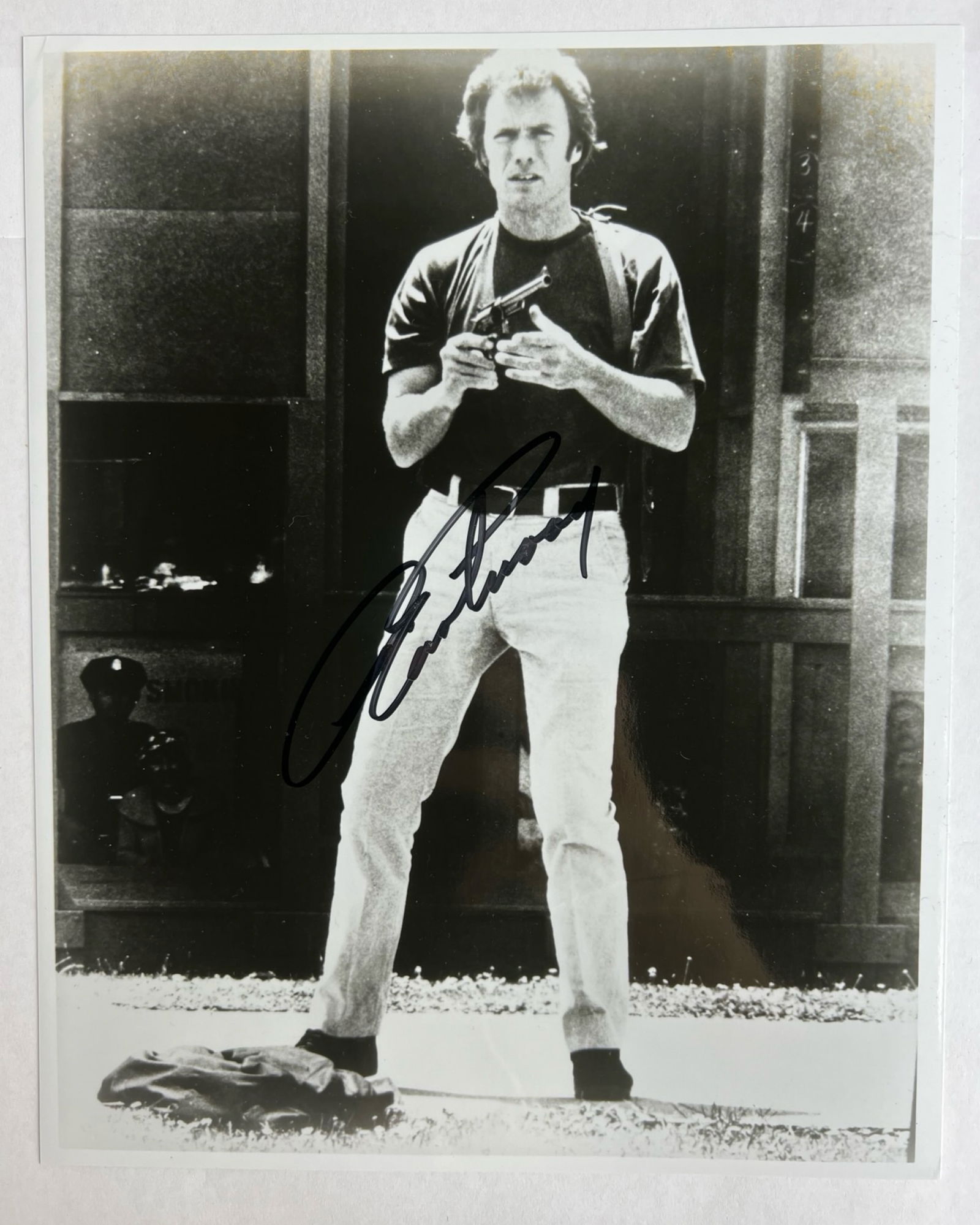 Clint Eastwood Signed "Dirty Harry" Photograph: Black-and-white photograph autographed by Clint Eastwood, shown in his iconic role as Inspector Harry Callahan from Dirty Harry. Eastwood is depicted holding a revolver in a classic stance, with a bol