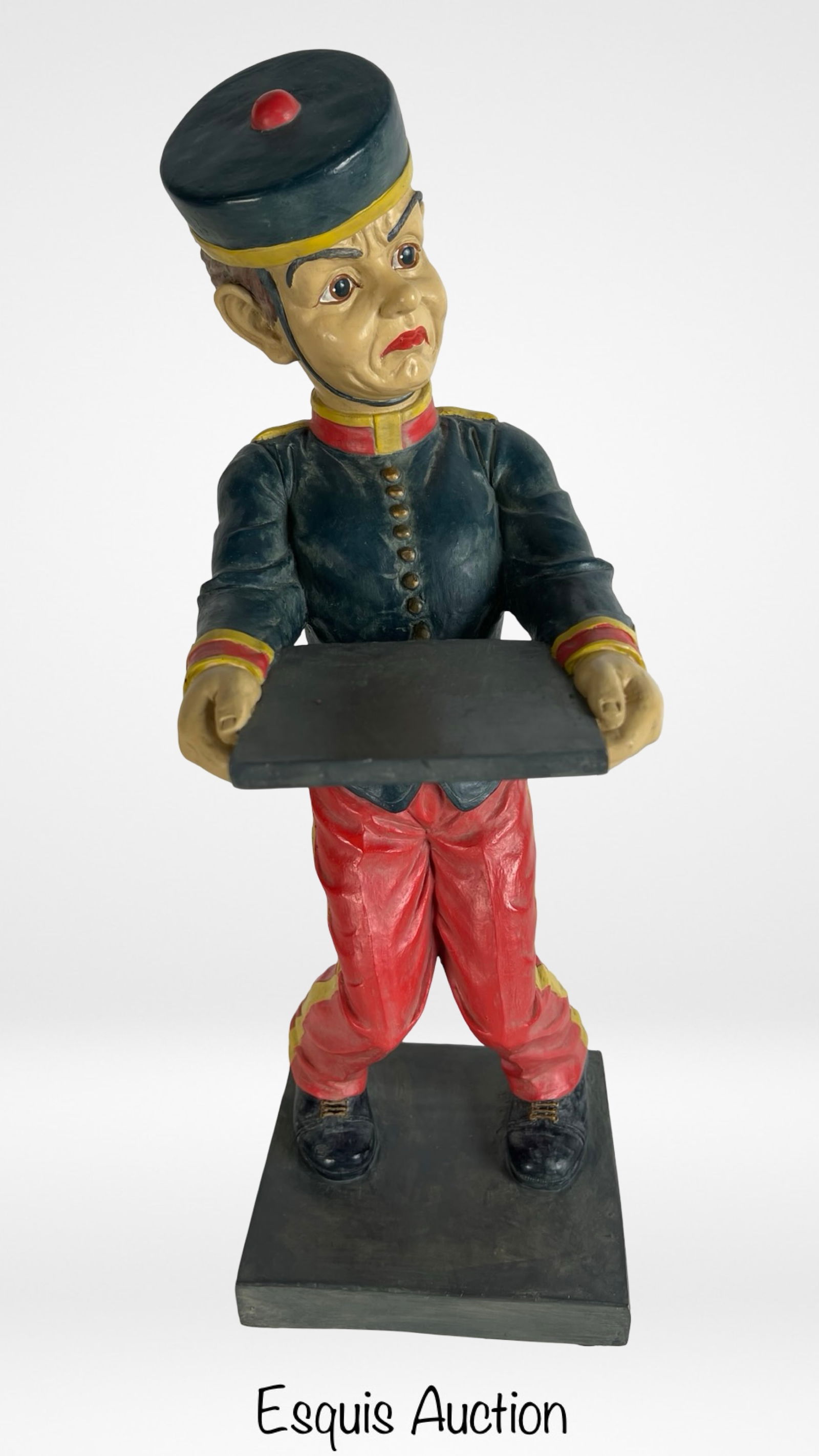 Johnny Roventini Style Bell Boy Statue: Charming painted statue of a bellboy in the style of Johnny Roventini, featuring exaggerated facial features and a colorful red, gold, and navy uniform. The figure holds a flat tray, ideal for use as