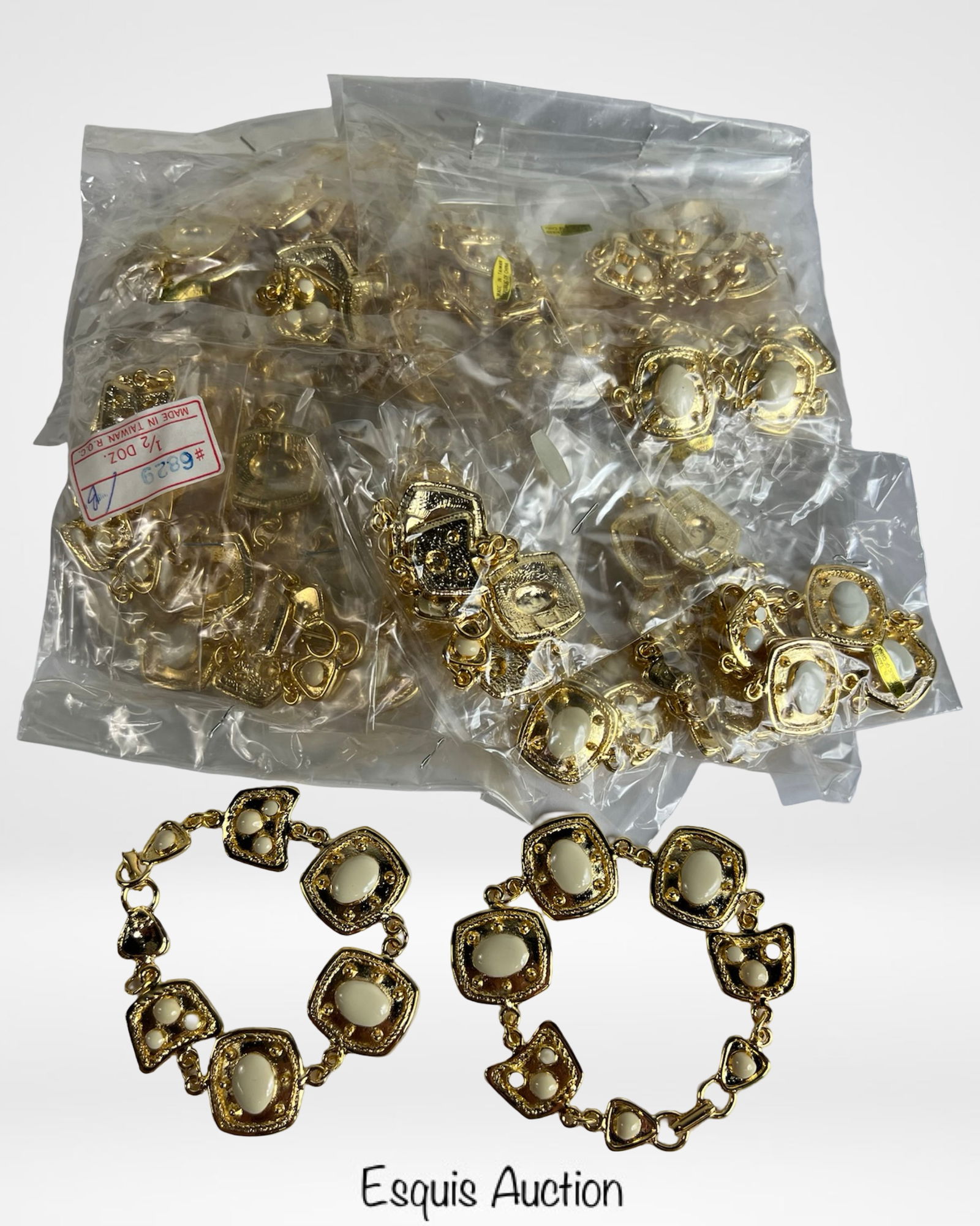 24 Gold-Tone Link Bracelets with Cream Inserts: Collection of two dozen elegant gold-tone link bracelets featuring geometric panels with cream-colored inserts. Each bracelet showcases vintage-inspired textured detailing and secure lobster clasp clo