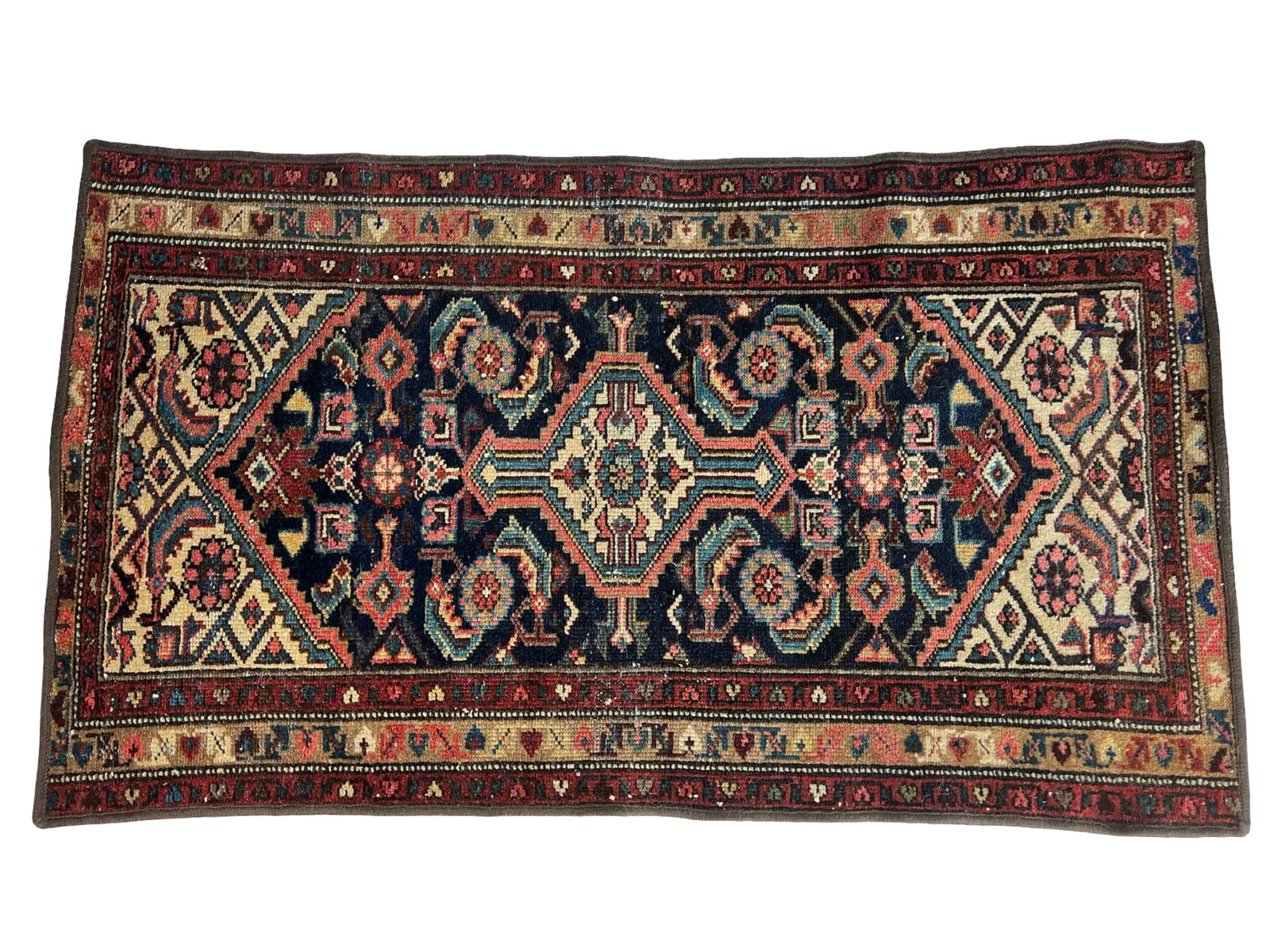 Vintage Heriz Hand-Knotted Wool Persian Rug: This Persian Heriz rug displays a striking geometric central medallion set against a deep navy field with stylized floral and angular motifs in shades of coral, ivory, sage, and blue. The balanced sym