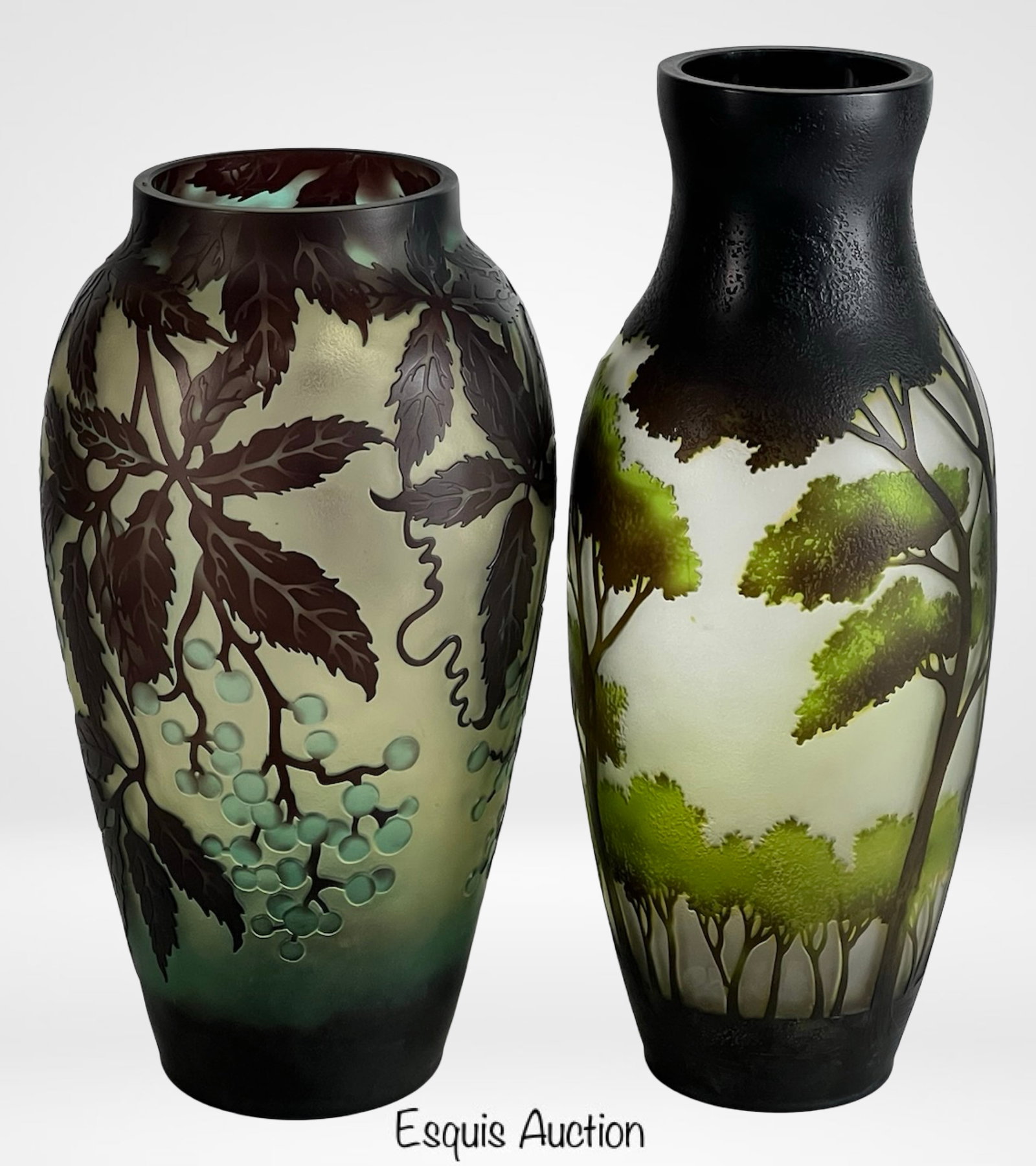 Galle Style Acid-Etched Cameo Glass Vases: Striking pair of Galle-style cameo glass vases, each showcasing intricate acid-etched landscape and botanical motifs in earthy tones of green, brown, and amber. One vase features a detailed grapevine 