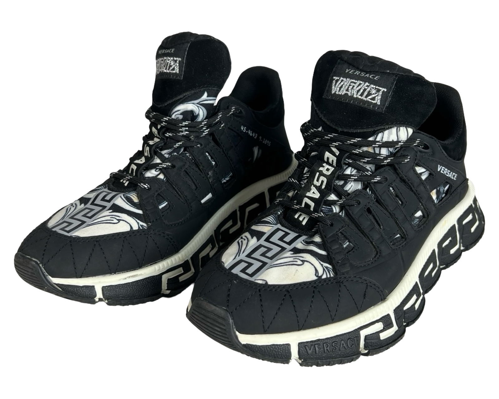 Versace Trigreca Black & White Sneakers - Size 41: Bold and graphic Versace Trigreca sneakers in black and white with Greca pattern uppers, logo-heavy construction, and geometric soles. Size 41, made in Italy. Pre-loved condition showing light wear to