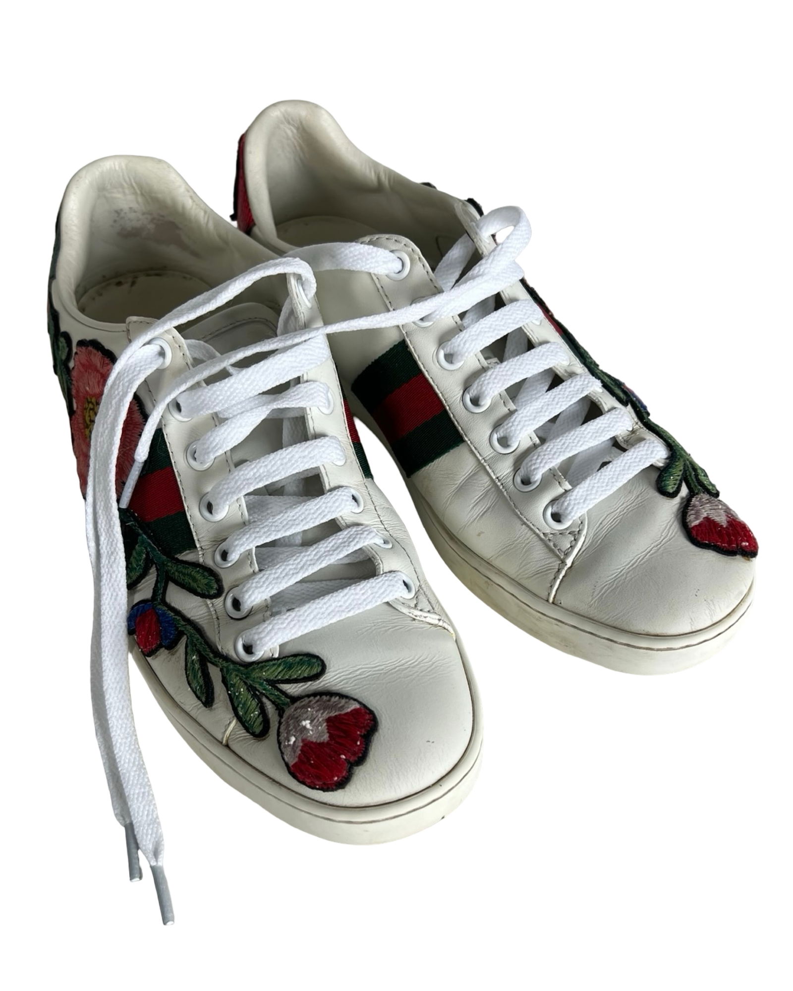 Gucci New Ace Floral Embroidered Leather Sneakers: These Gucci New Ace sneakers feature white leather uppers beautifully detailed with vibrant floral embroidery and classic green-red-green web stripes. Designed with metallic red and green snakeskin he