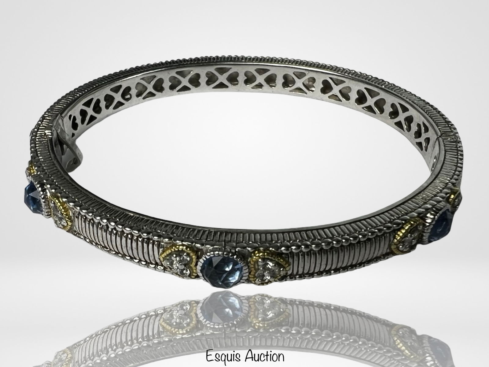 Judith Ripka Sterling Silver & 18K Gold Bracelet: Elegant hinged bangle bracelet by Judith Ripka, crafted in sterling silver with intricate heart and X-pattern piercings on the inner band. The outer surface features finely textured silverwork accente