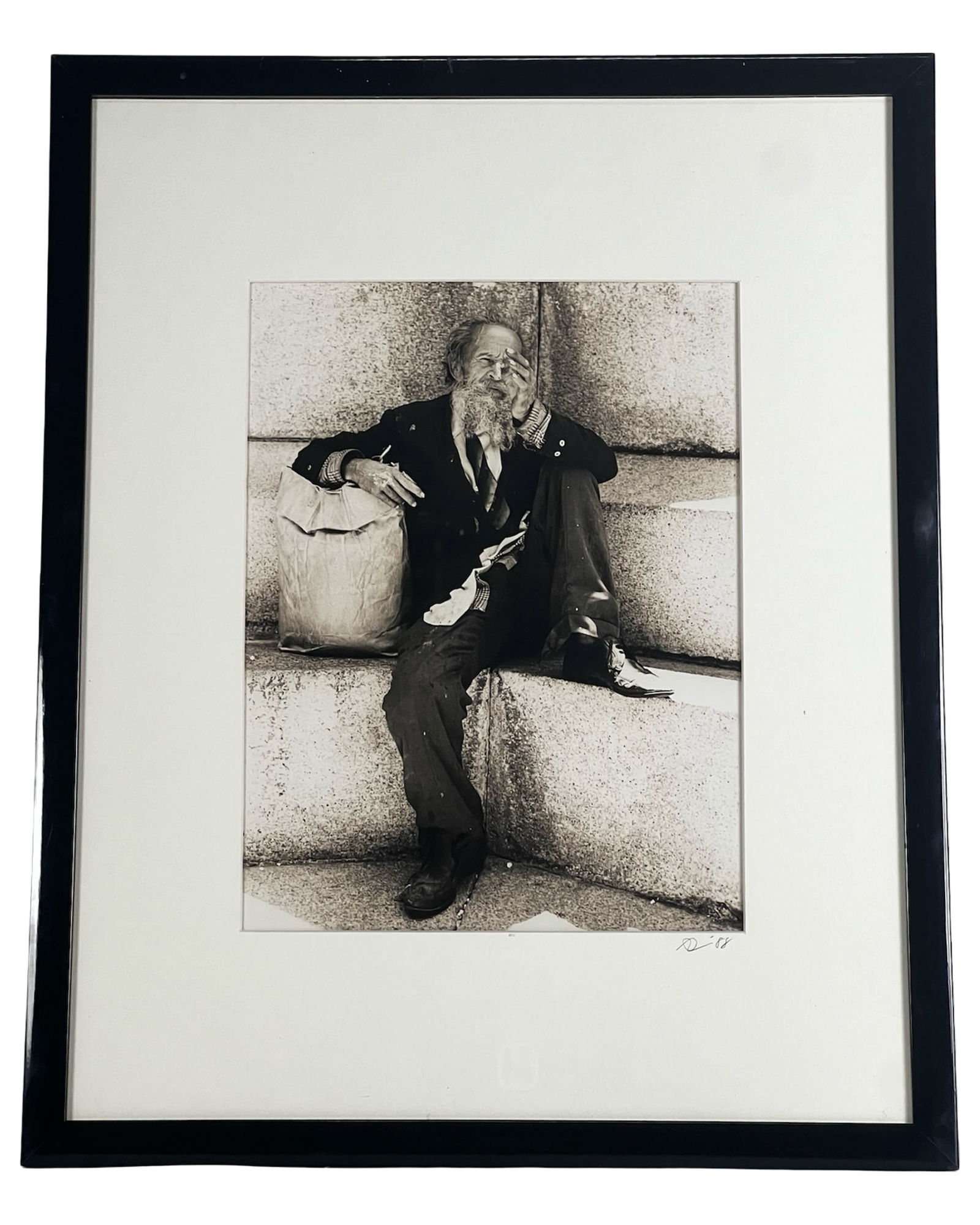 Seated Bearded Man- Signed Gelatin Silver Print: Striking gelatin silver photographic print dated '88, depicting a candid street-style portrait of an older man seated on large stone steps, captured in rich contrast and expressive detail. The bearded